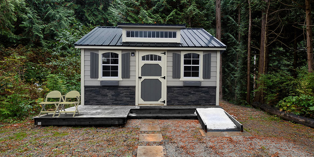 Custom-built shed with double doors, decorative shutters, and stone siding accents, designed for durable backyard storage in Maine
