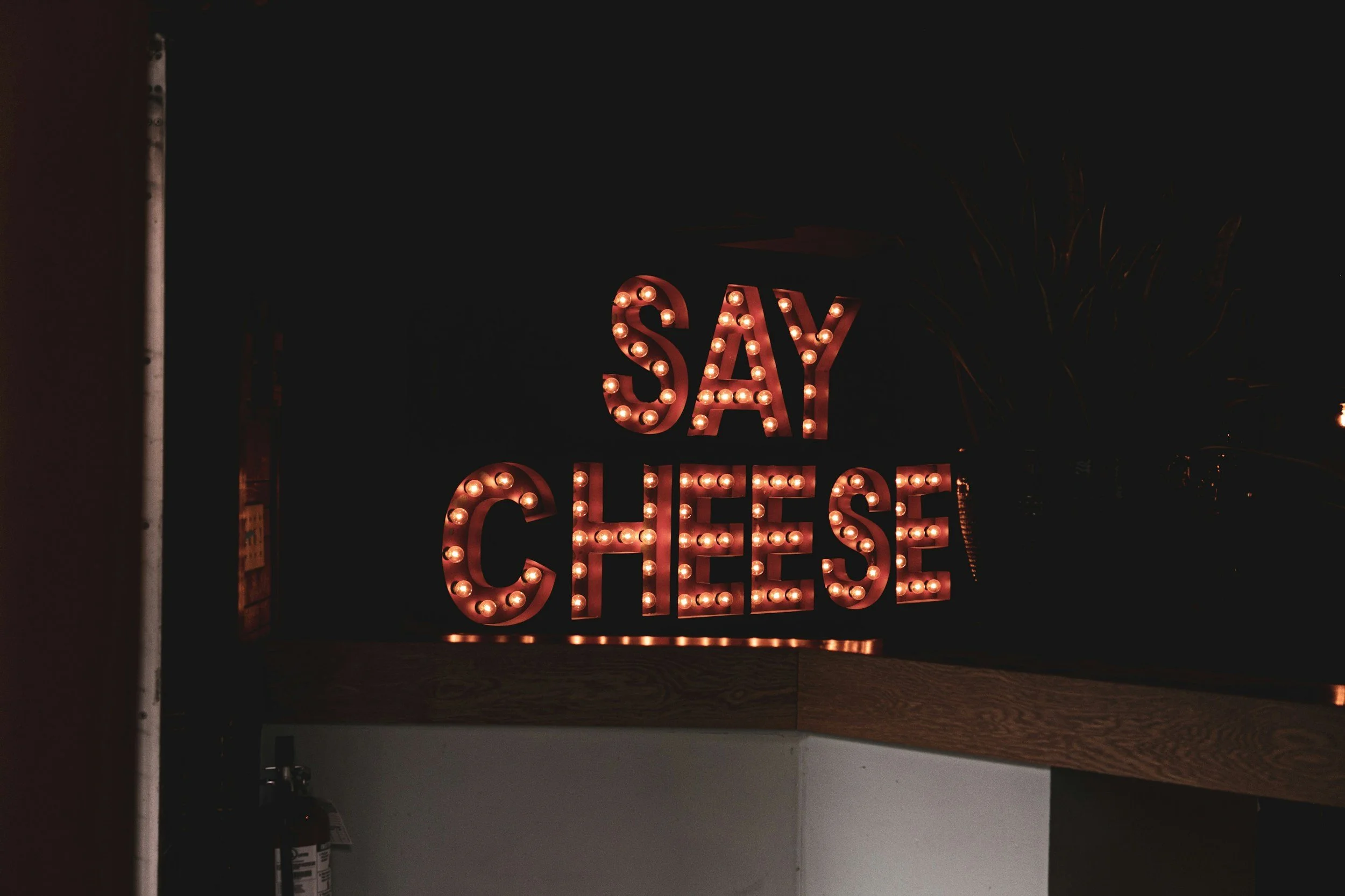 un banner luminos pe care scrie cu beculete portocaliu aprins " SAY CHEESE"