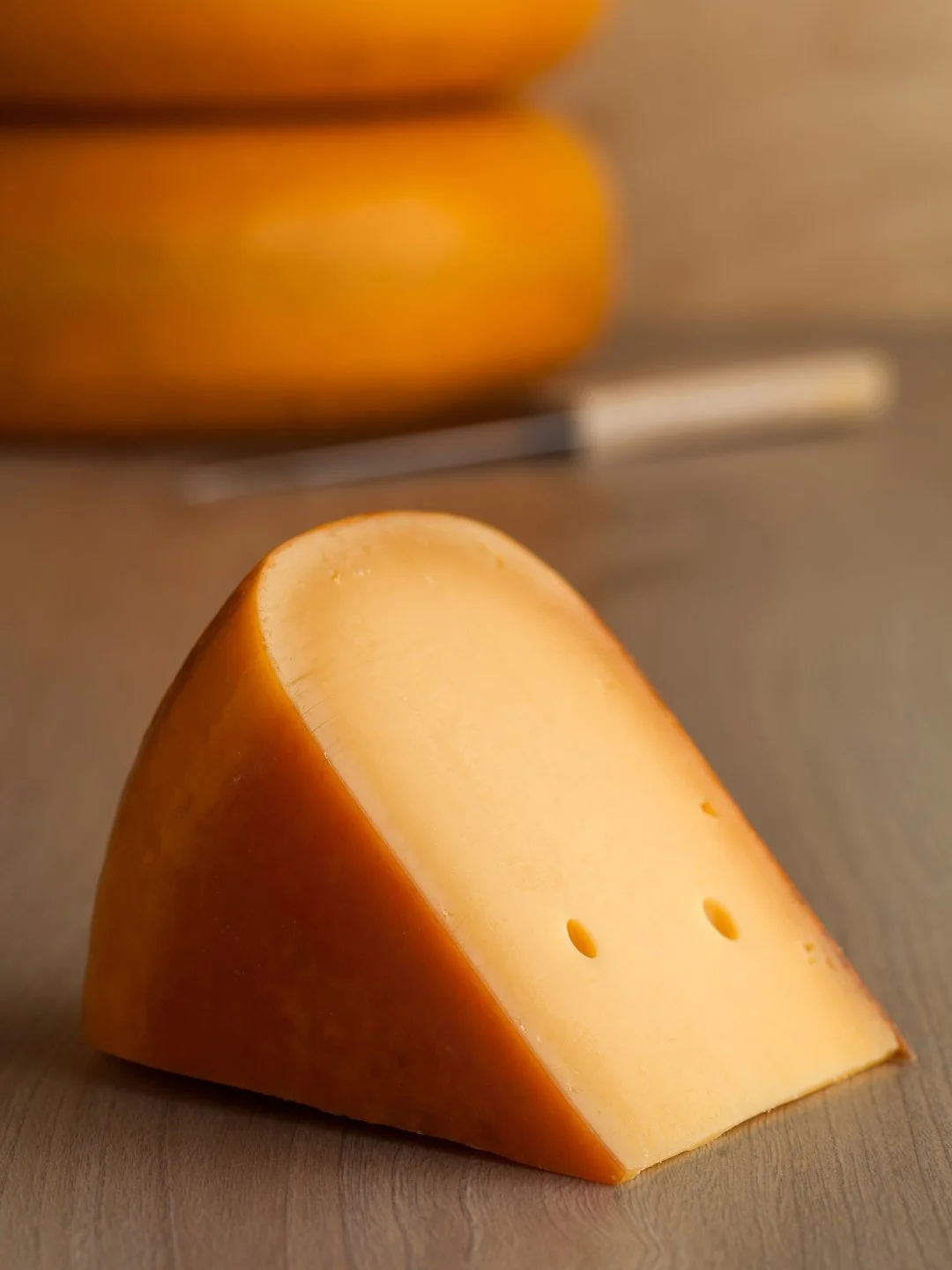 o bucata de branza Gouda pe masa de lemn