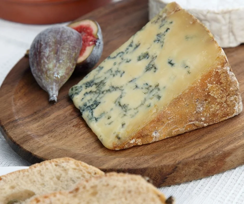 Bucata de branza stilton pe locator de lemn alaturi de smochine si paine