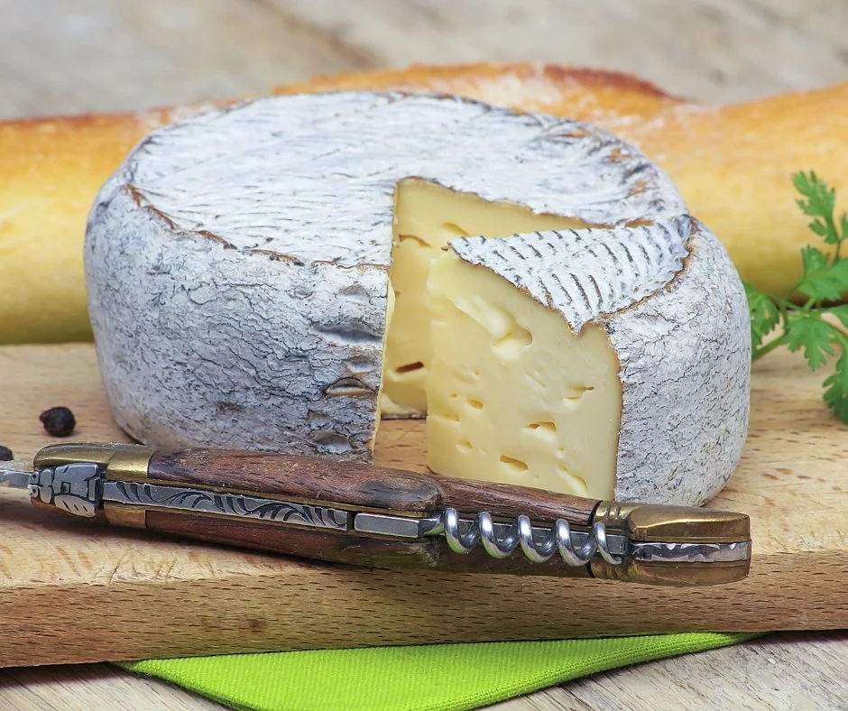 branza cu coaja naturala pe un suport de lemn cu un cutit alaturi