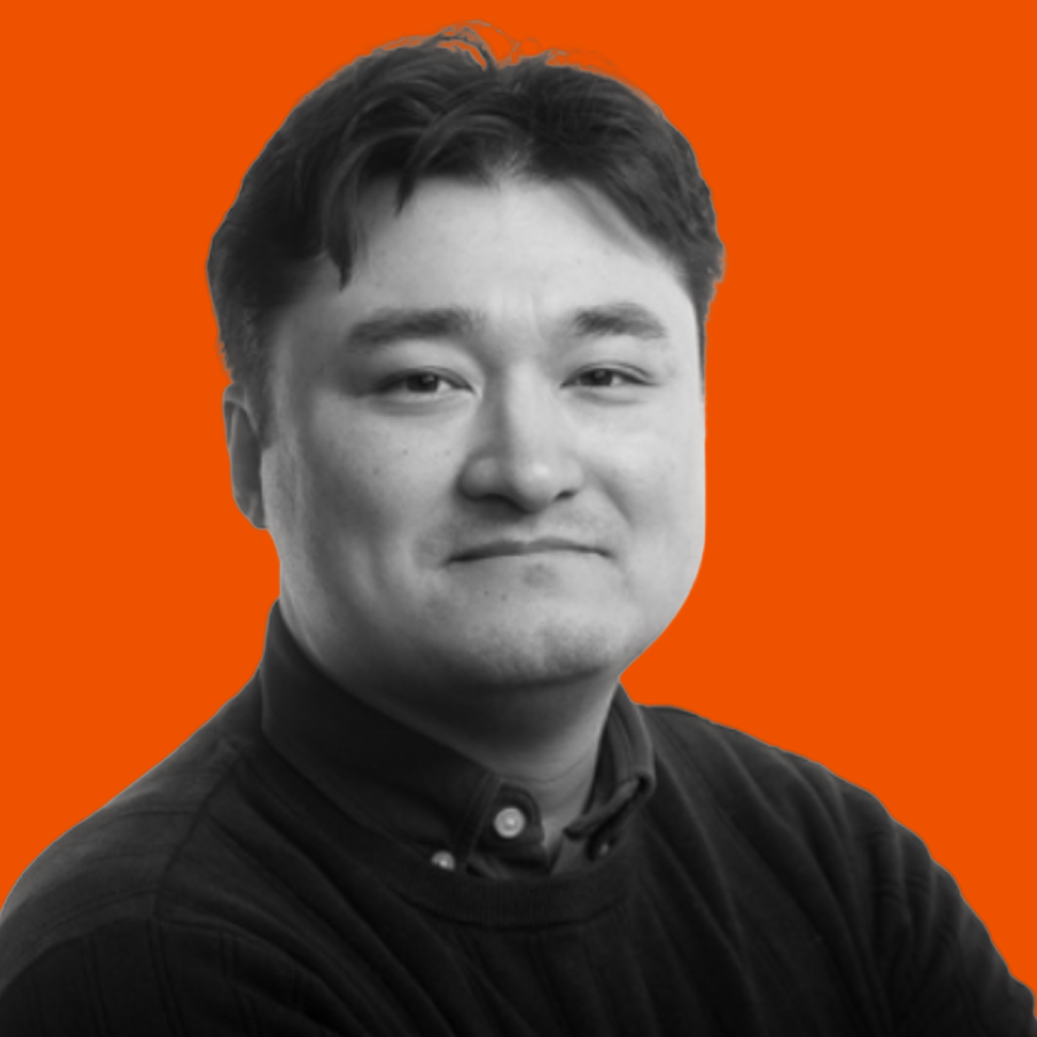 Black and white portrait of a young man with short dark hair, wearing a dark collared shirt, set against an orange background.