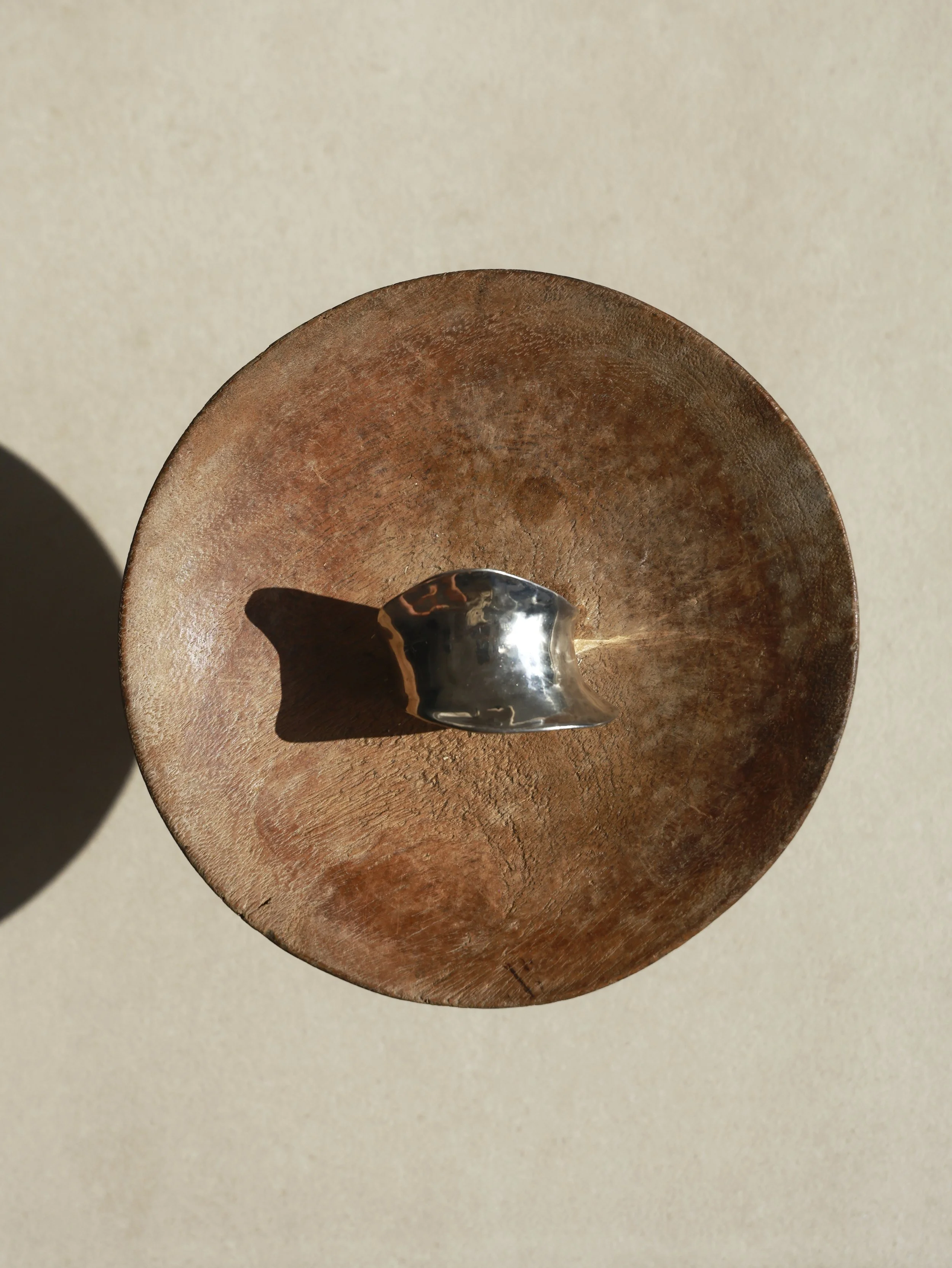 Close-up of a metallic object measuring the thickness of a wooden surface, with a smooth metallic tool resting on the wood.