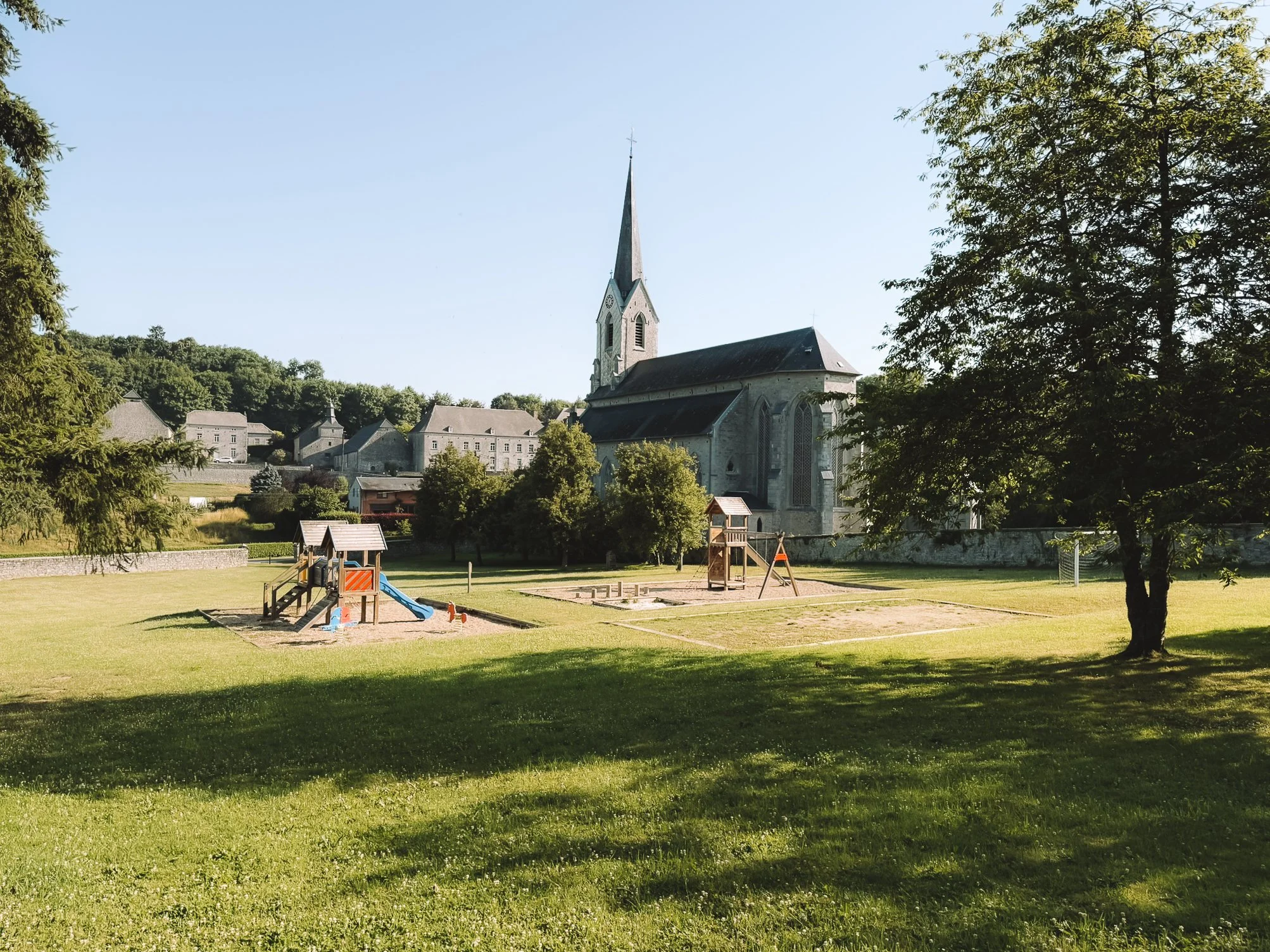 Een kindvriendelijk park met speeltuin en een kerk op de achtergrond.