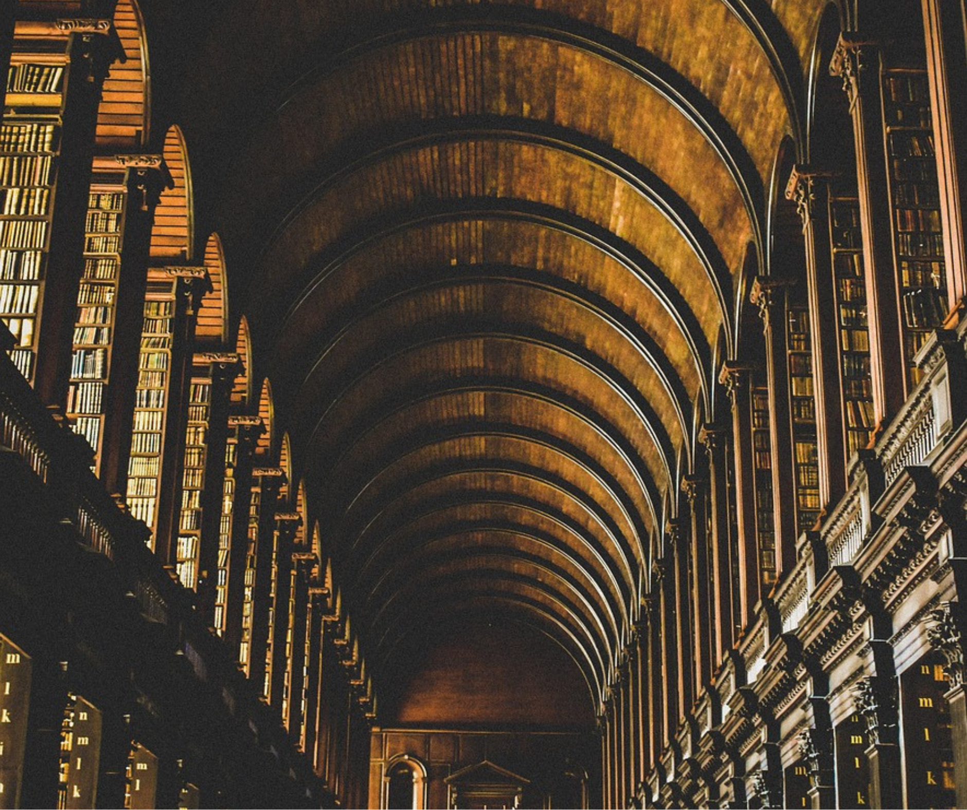 A large historic university library with wooden arches and bookshelves, reflecting academic environments tied to college admissions counseling.