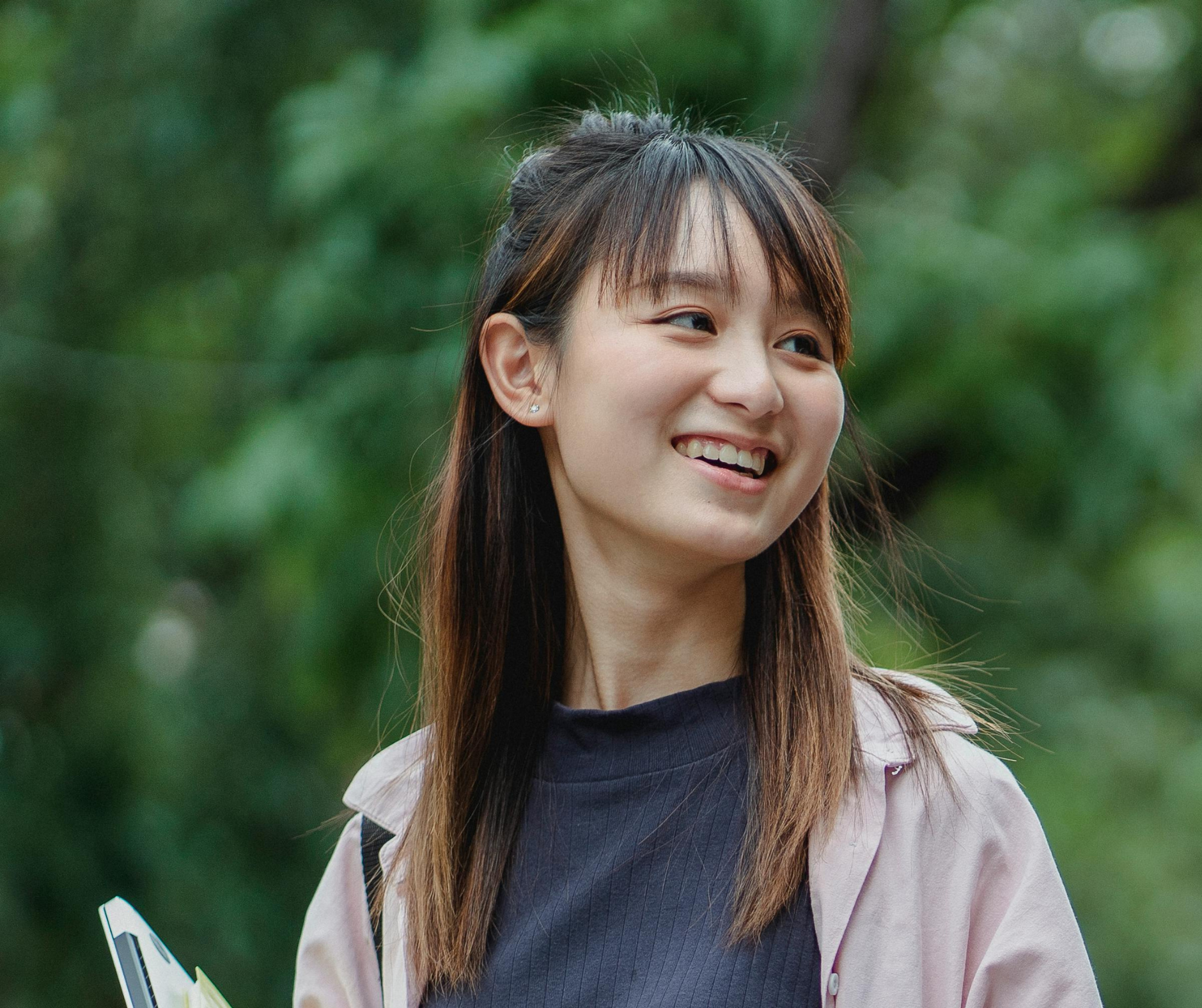 A smiling student stands outdoors holding books, reflecting confidence and preparation supported by college admissions consulting services.