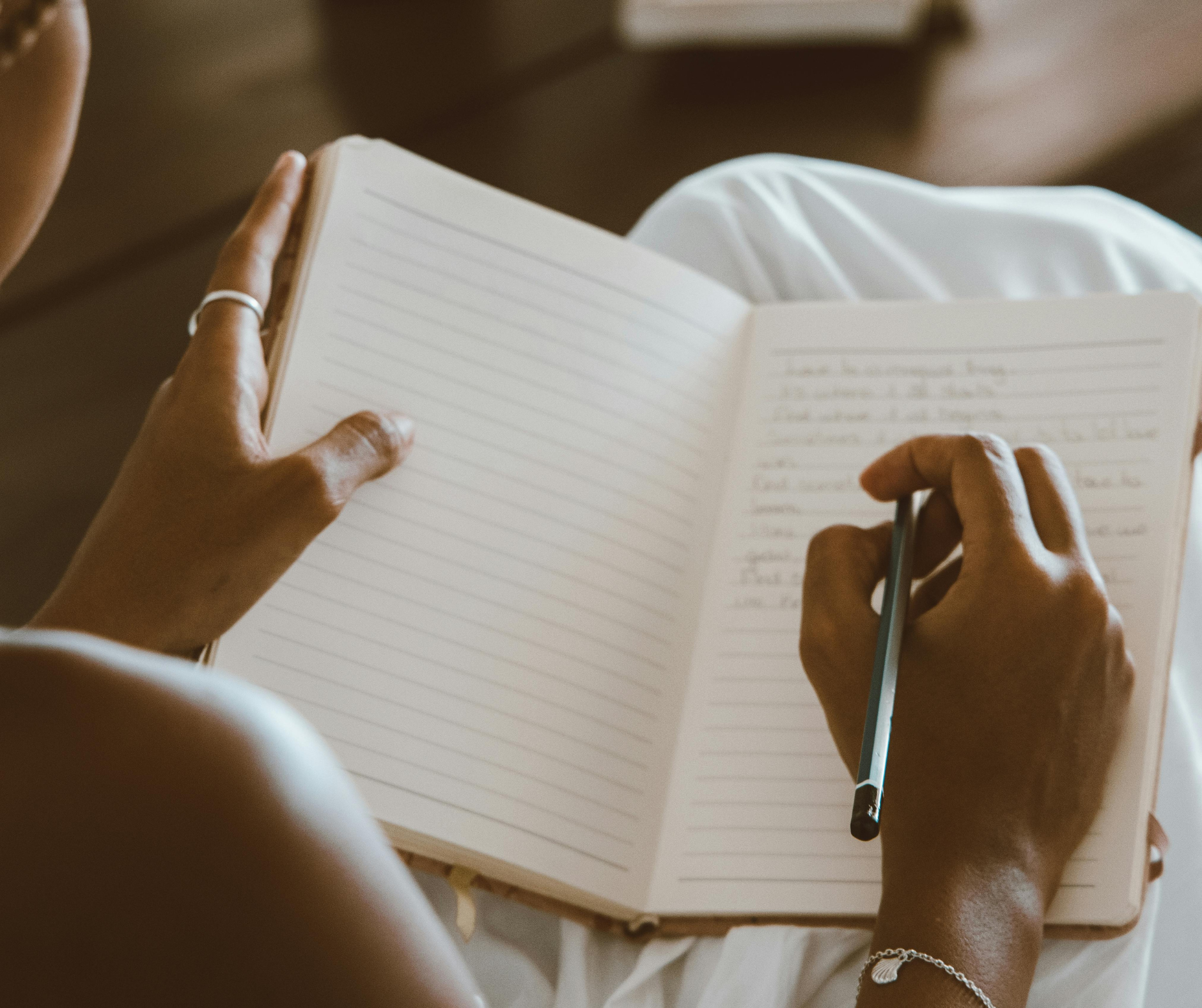 Student writes in a lined notebook while preparing materials for college admissions consulting and organizing application ideas.