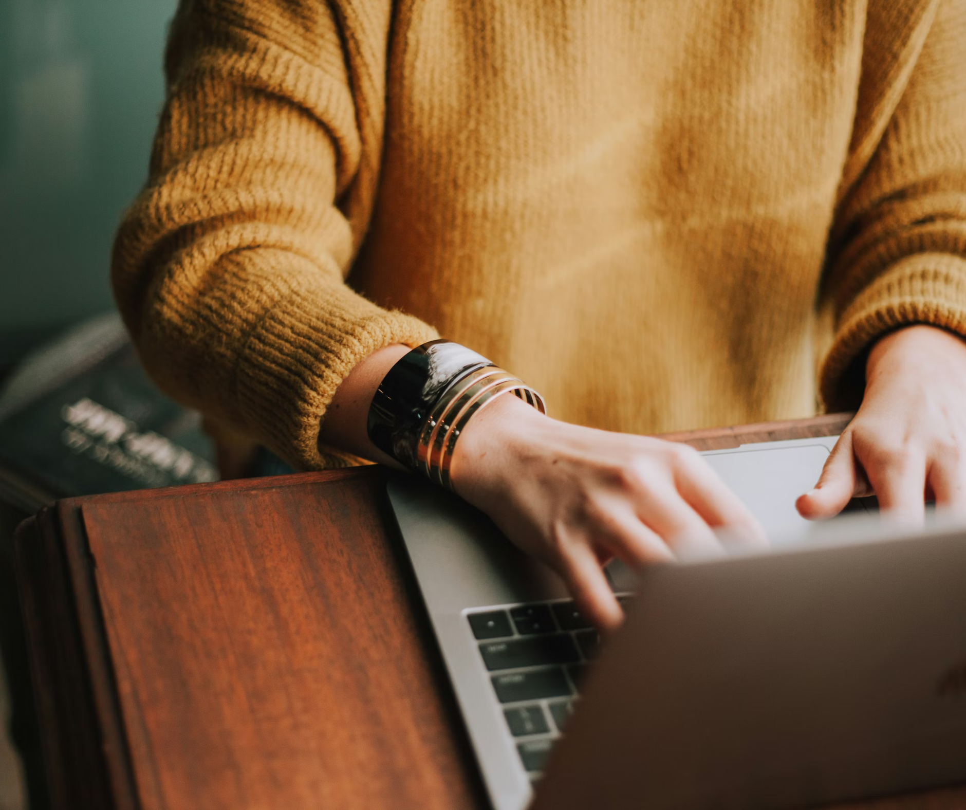Student types on a laptop at a wooden desk while researching college admissions consulting services and preparing application materials.