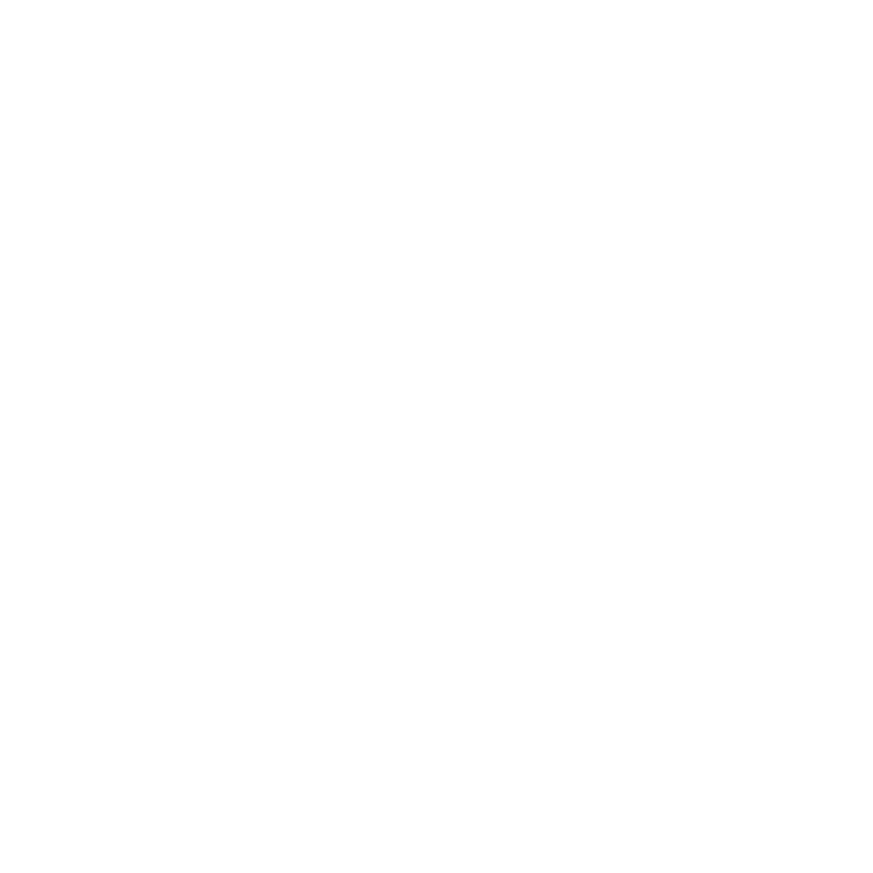 A man with a beard and plaid shirt working with a vintage orange sewing machine at a wooden table in a workshop.