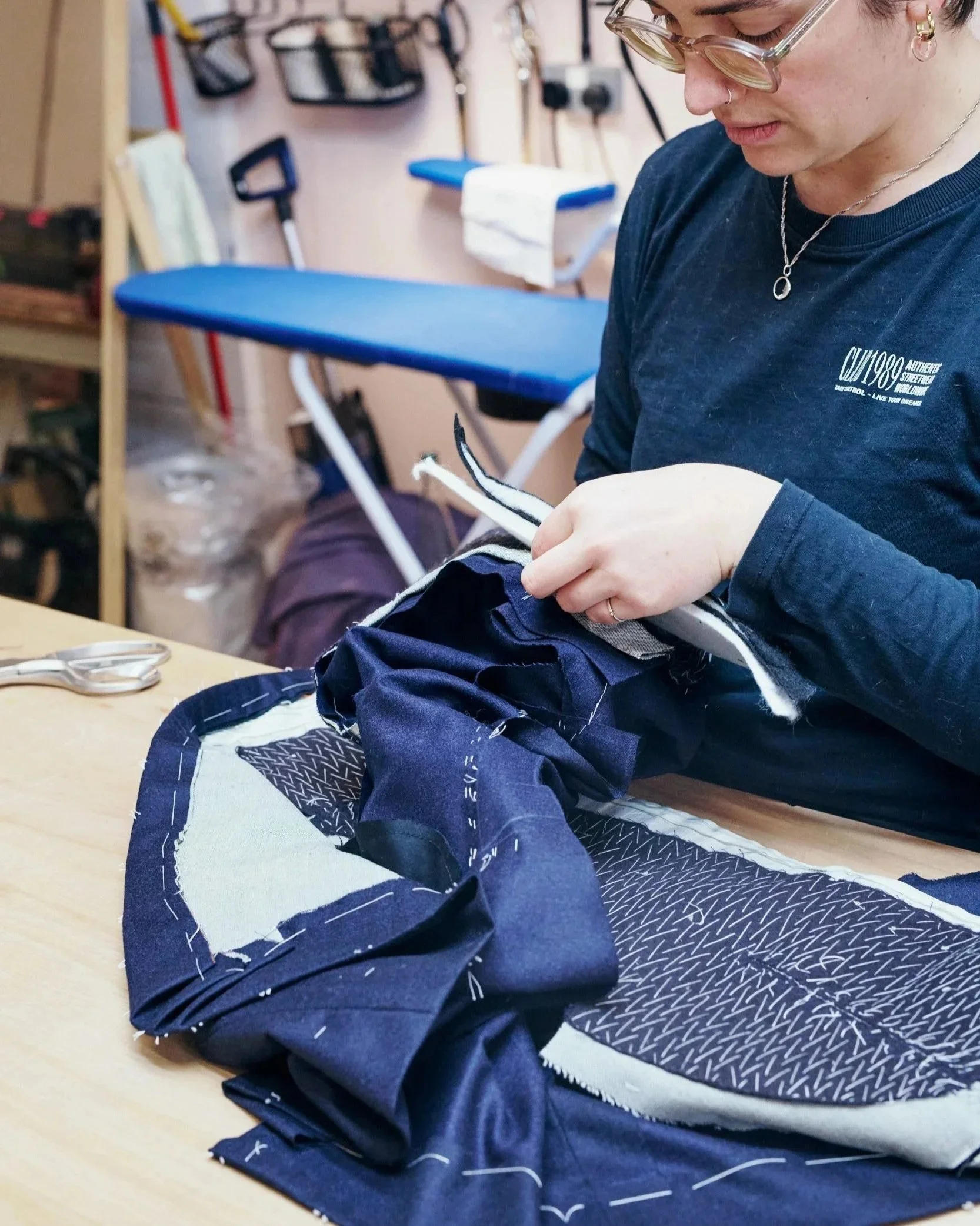woman sewing shoulder pads into a blue garment