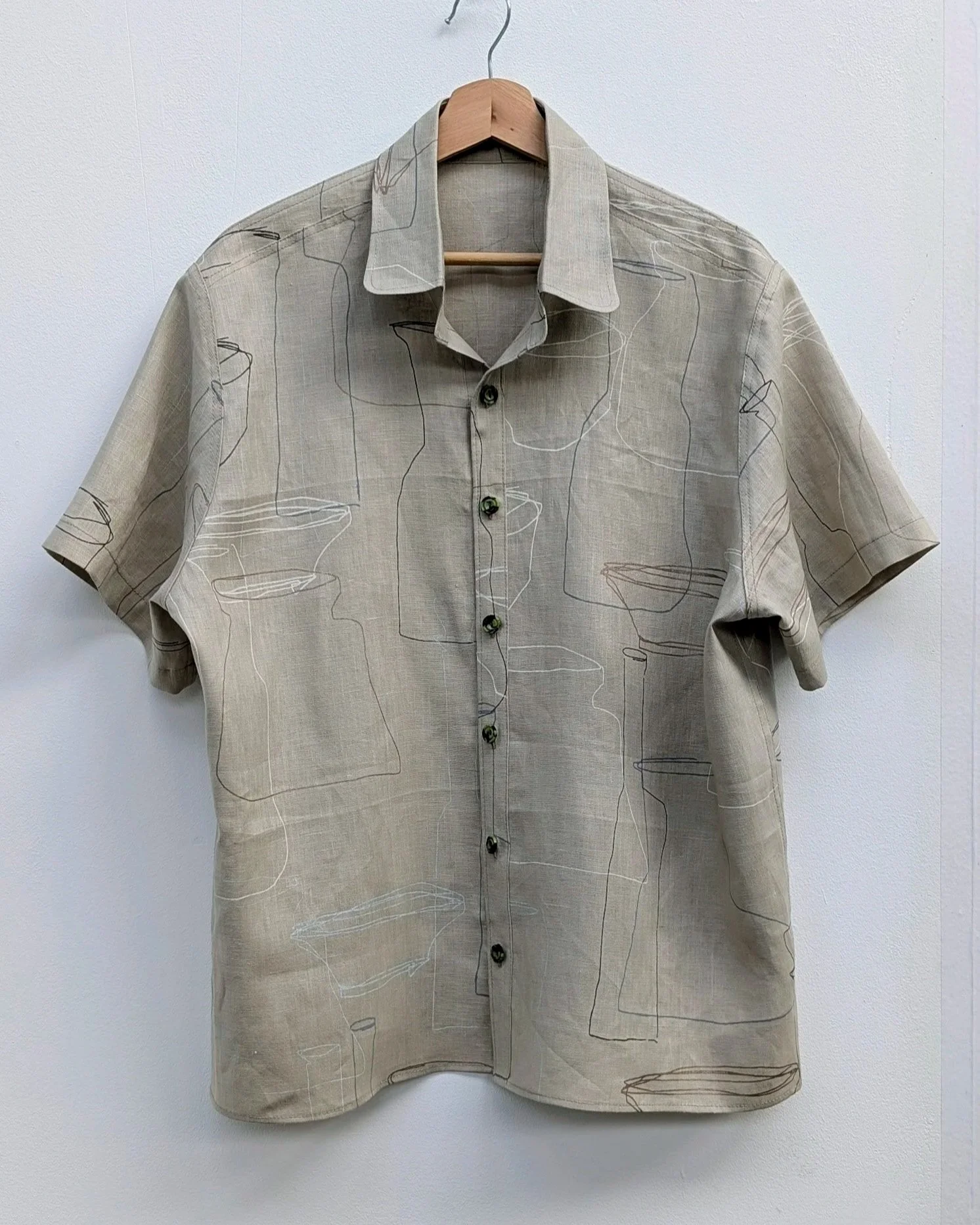 A beige short with printed pattern hanging in front of a white background