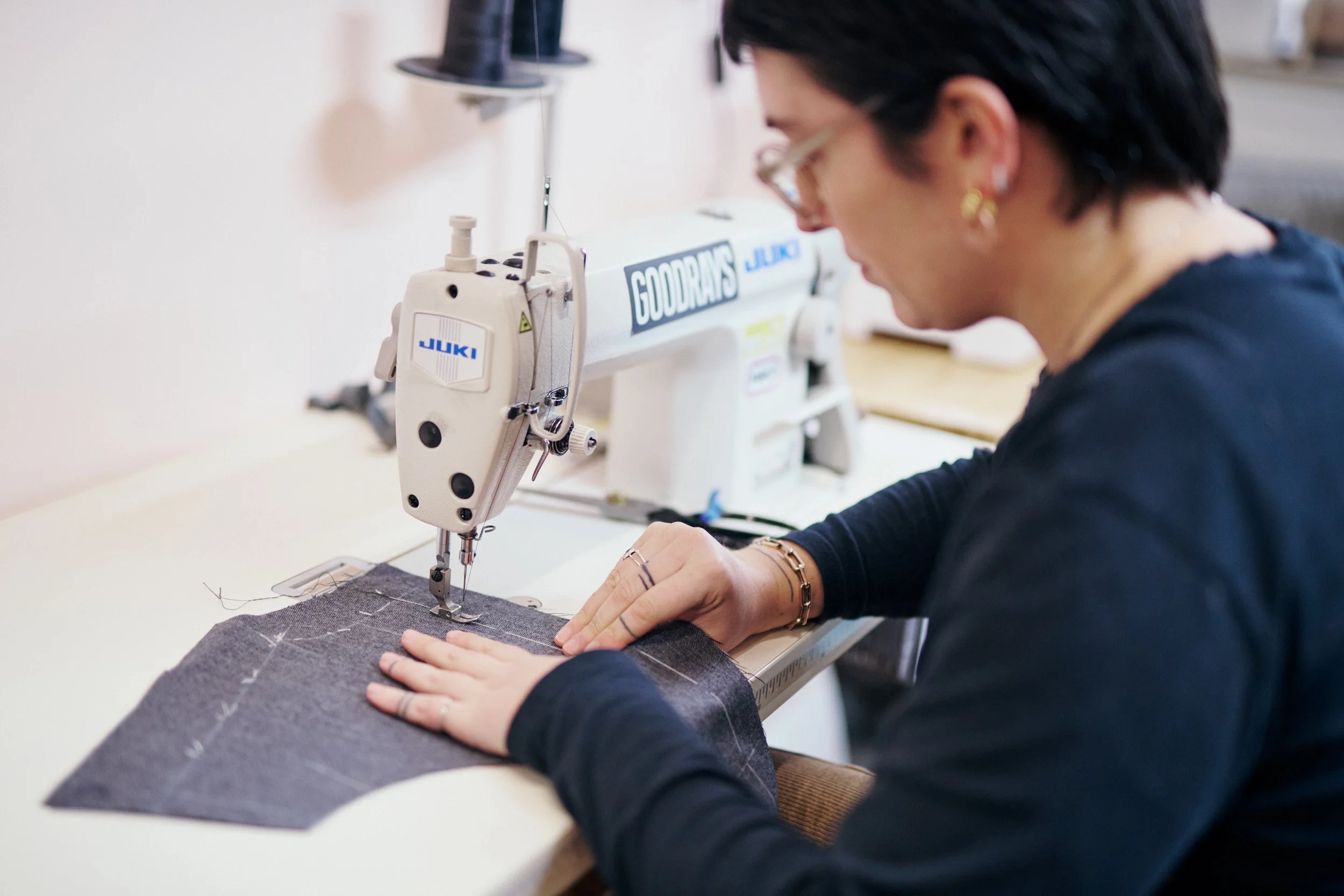 A woman sewing fabric on a sewing machine in a workshop.