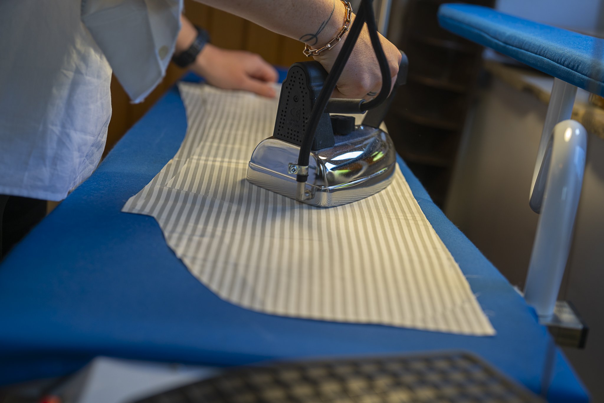 Person ironing striped fabric on an ironing board.