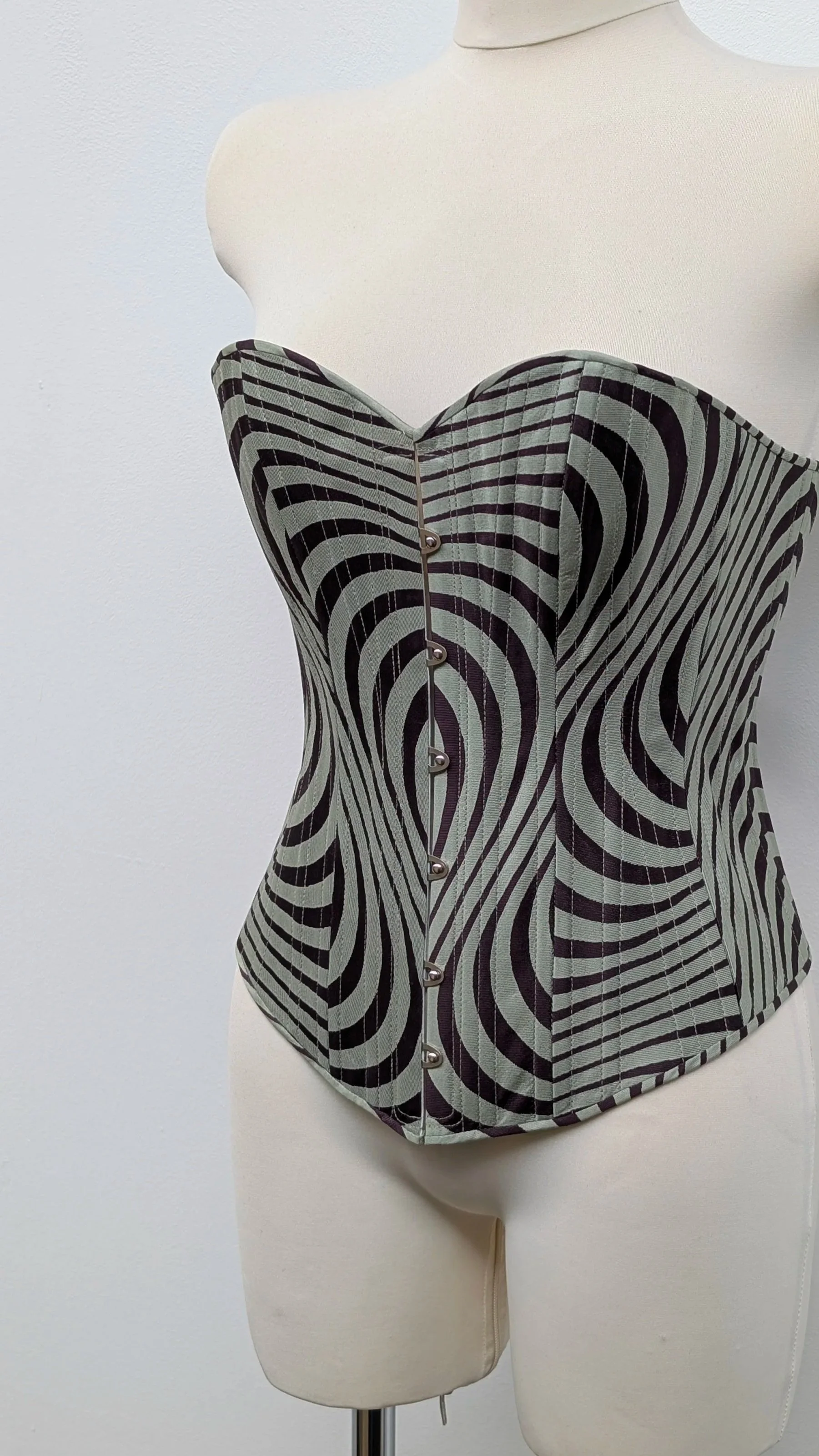 a corset with wavey stripes on a mannequin with a white background