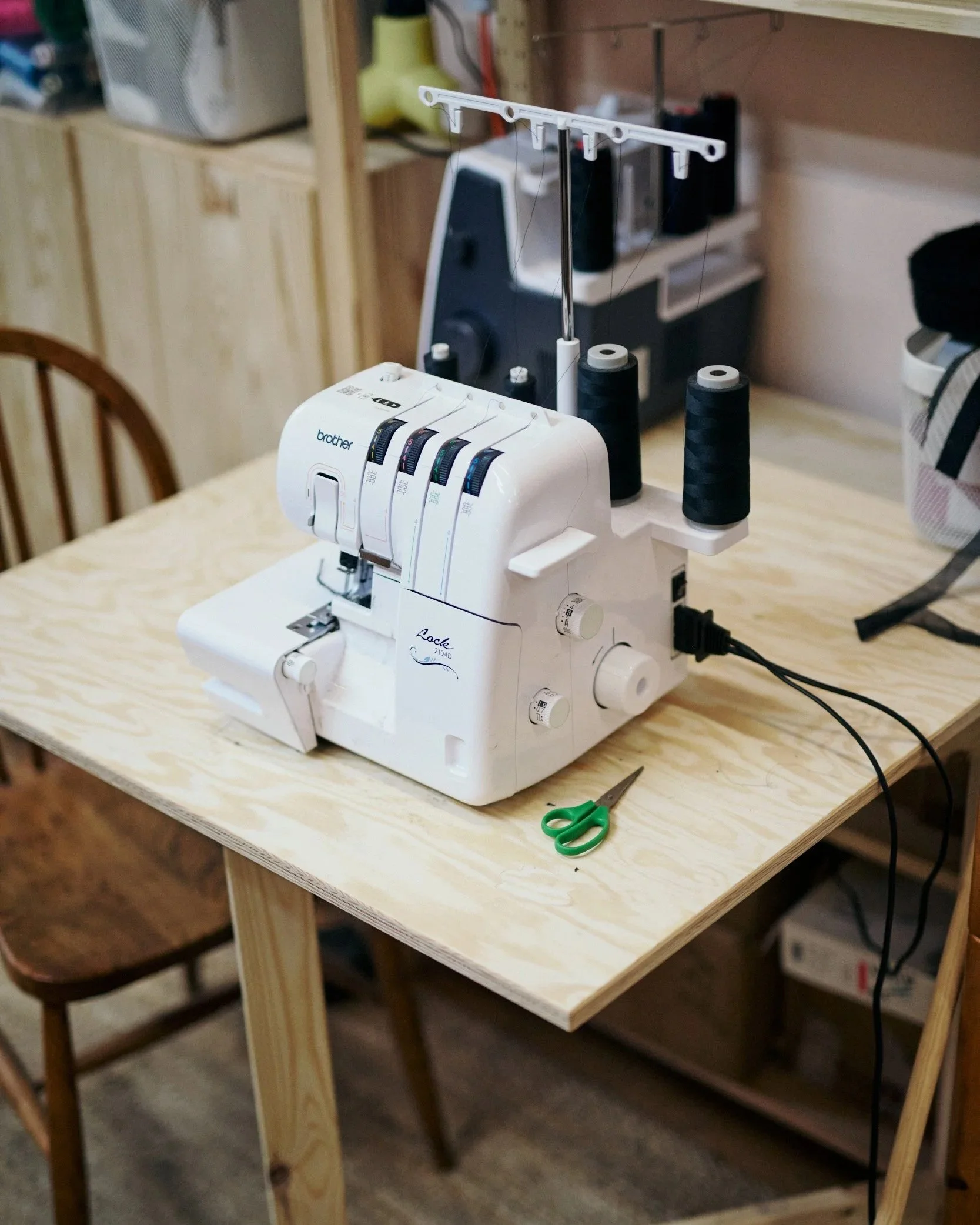 A sewing machine on a wooden table with scissors nearby in a craft room.