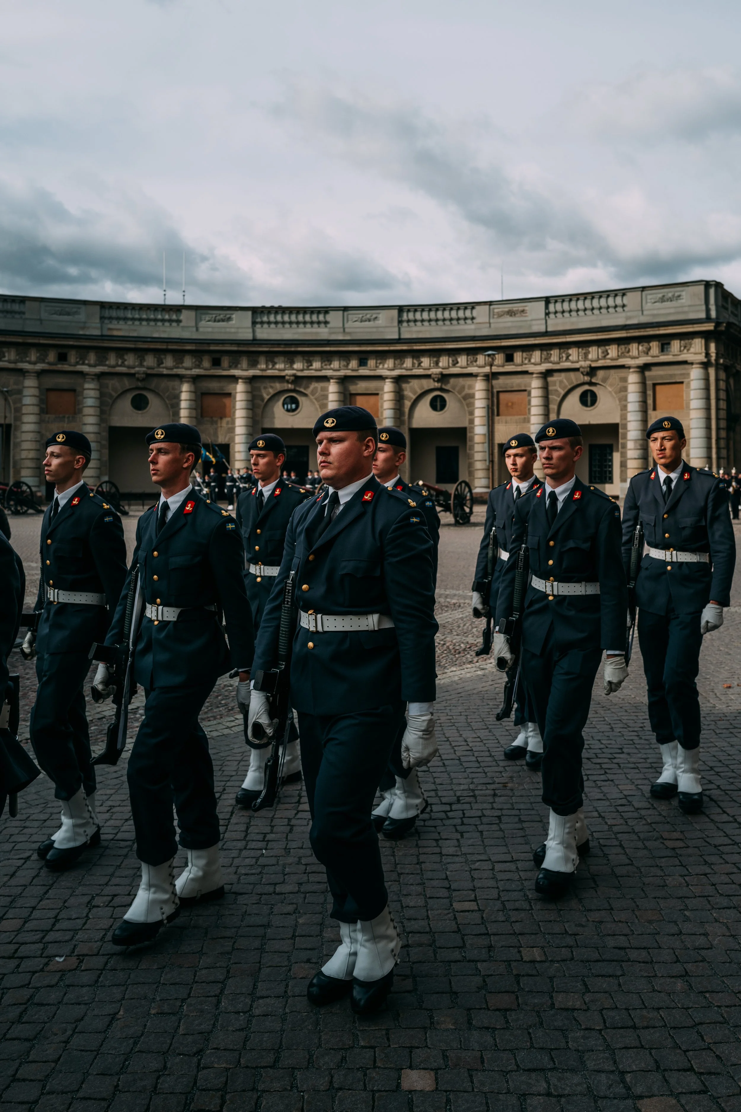 Group of soldiers in uniform marching in formation during a military ceremony in an outdoor courtyard
