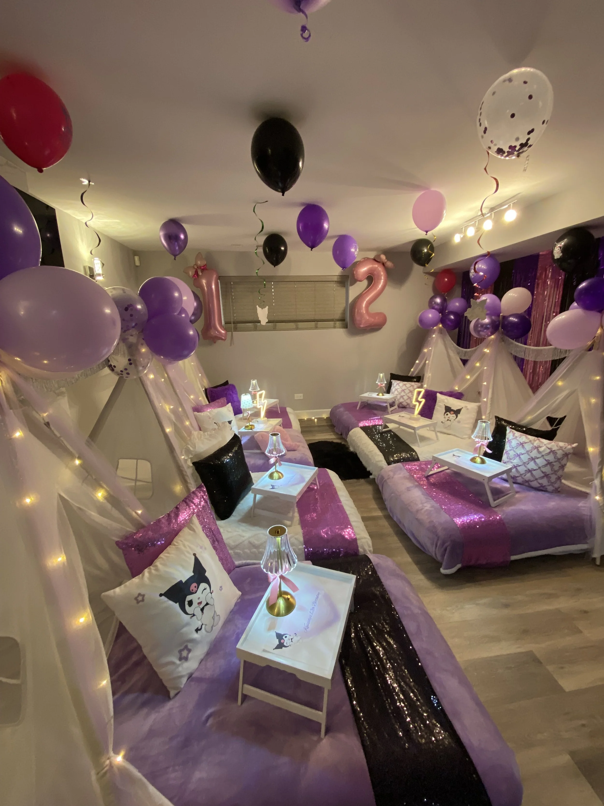 People watching an outdoor movie on inflatable screen displaying 'Monte Carlo' at night with palm trees, string lights, and a candle on a small table.