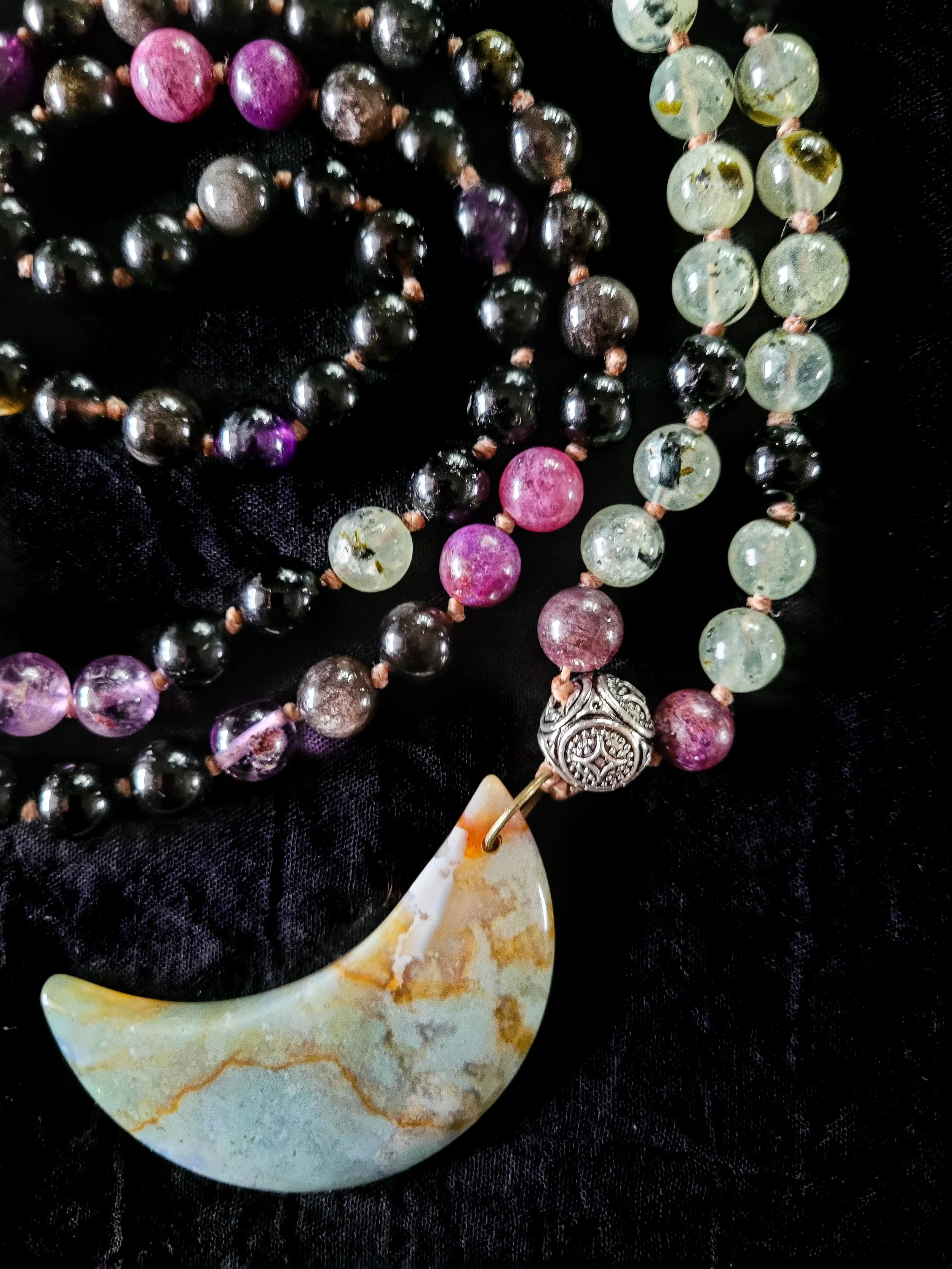Photo custom-made limited gemstone mala necklace with 6mm super seven amethyst, prehnite, rainbow and black tourmaline, and silver sheen obsidian round gemstones; 4mm ornate round silver bead; and large light green and brown moss agate crescent-moon 