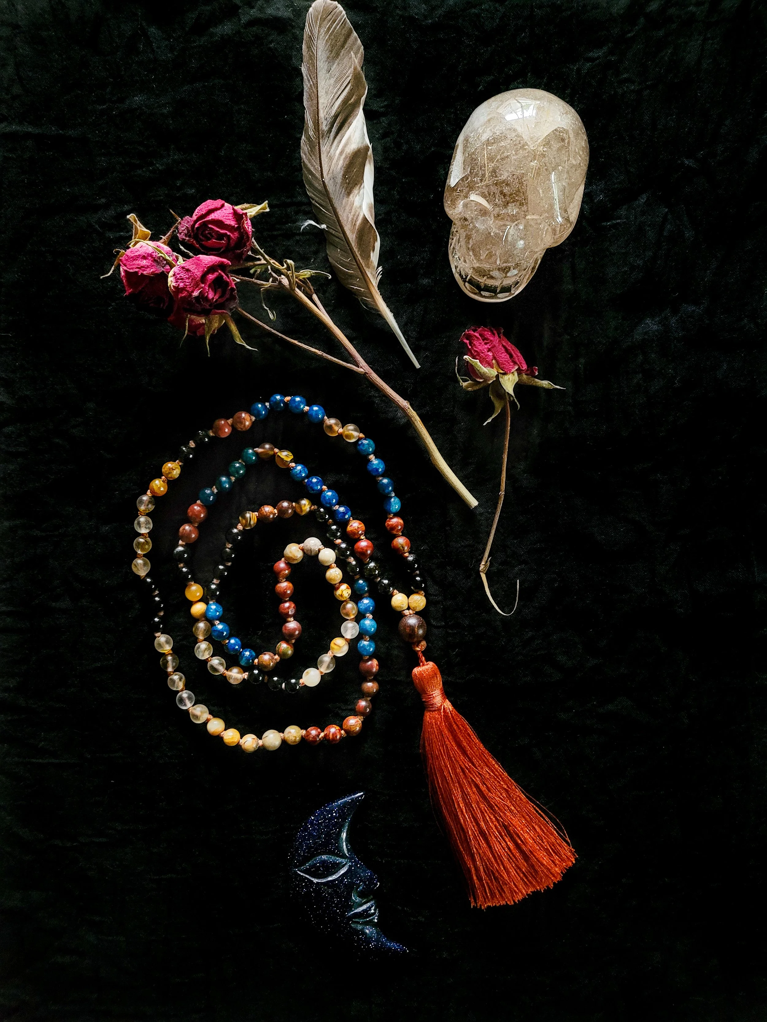 Photo of custom-made limited gemstone mala necklace with 8mm tourmaline, yellow jade, amazonite, picture and crazy horse jasper, fire agate, lapis lazuli; 6mm sandalwood bead; and dark orange silk tassel. Feather, crystal skull, blue crystal moon, fe