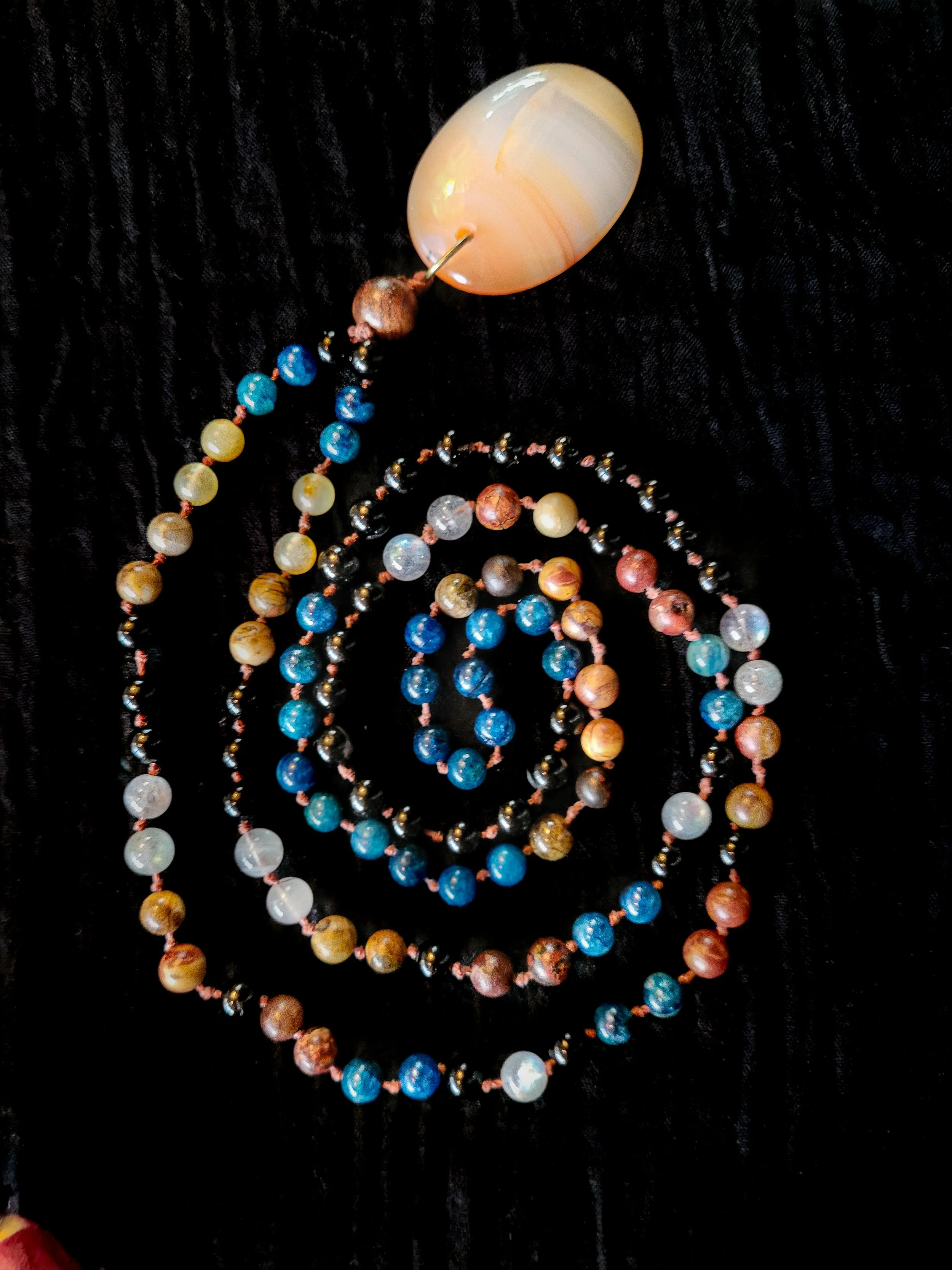 Photo of custom-made limited gemstone mala necklace with 8mm labradorite, lapis lazuli, crazy horse Jasper, tourmaline; 10mm sandalwood bead; and carnelian pendant. Commission designed, handmade, & photographed by Afro-Indigenous artist Siobhan Kekoa