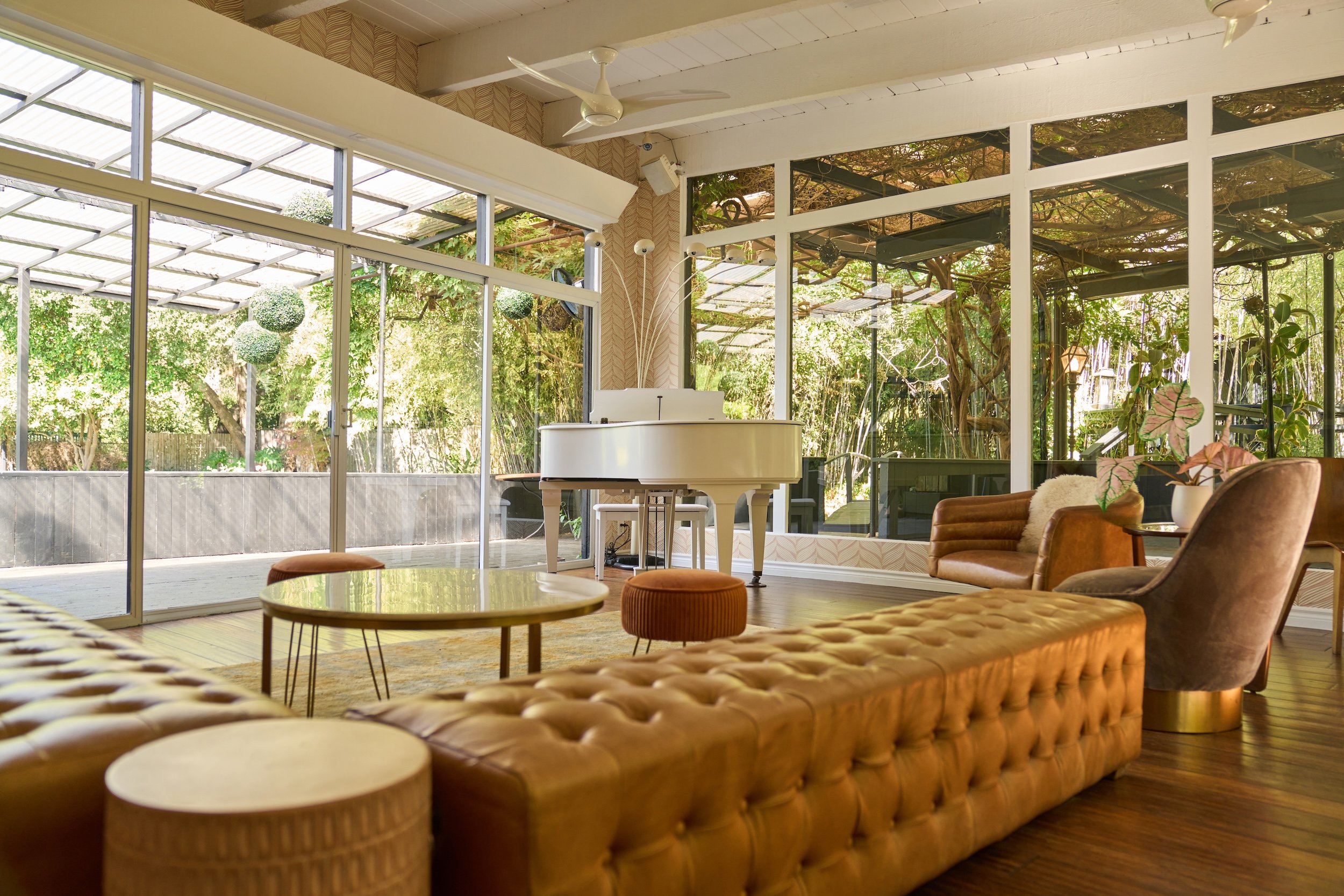 Framed by floor-to-ceiling windows, our bar lounge invites guests to settle in—whether they’ve arrived early or simply aren’t ready to say goodbye. The grand piano rests in the corner, occasionally coming to life, while the surrounding garden remains