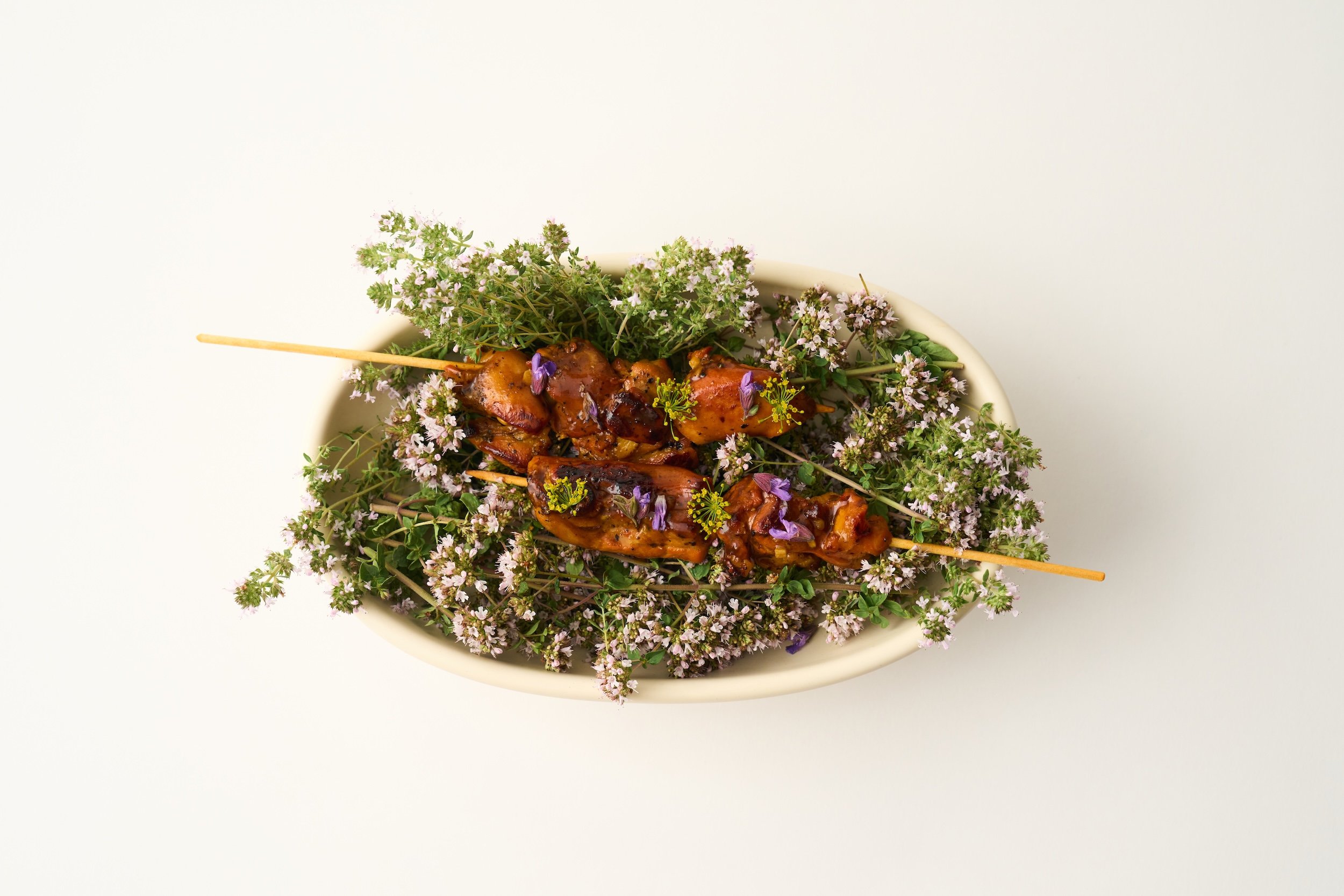 A snack worth lingering over — chicken thighs on a skewer, kissed by charcoal and inspired by the classic Spanish pincho moruno. Herb-laced, spice-packed, and smoky in all the right ways. Grilled over coals, just steps from the garden.
