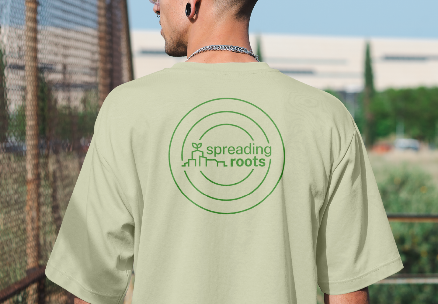man wearing green t-shirt with spreading roots logo printed on the back