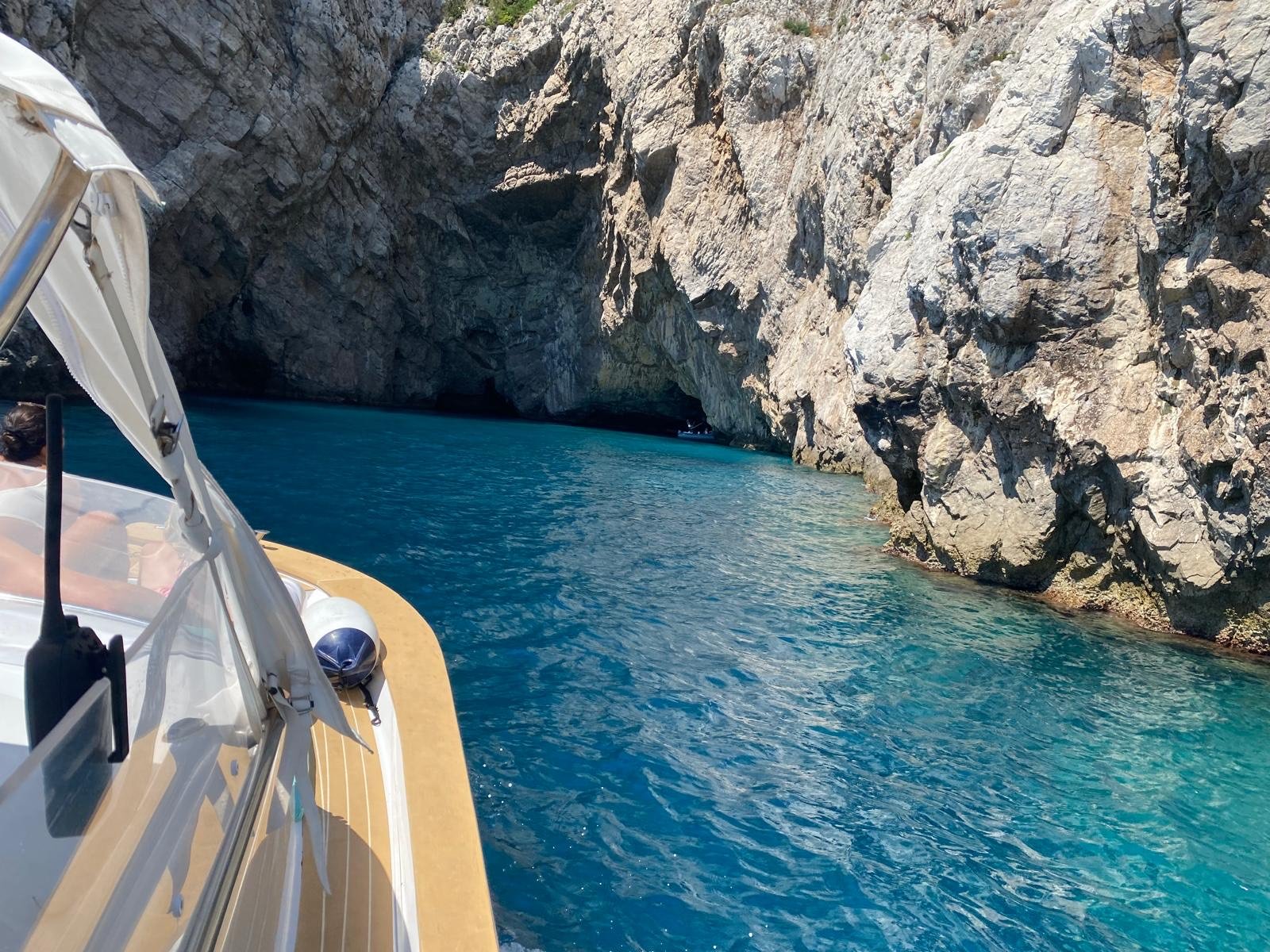 A boat navigating through a narrow, rocky canyon with clear blue water.