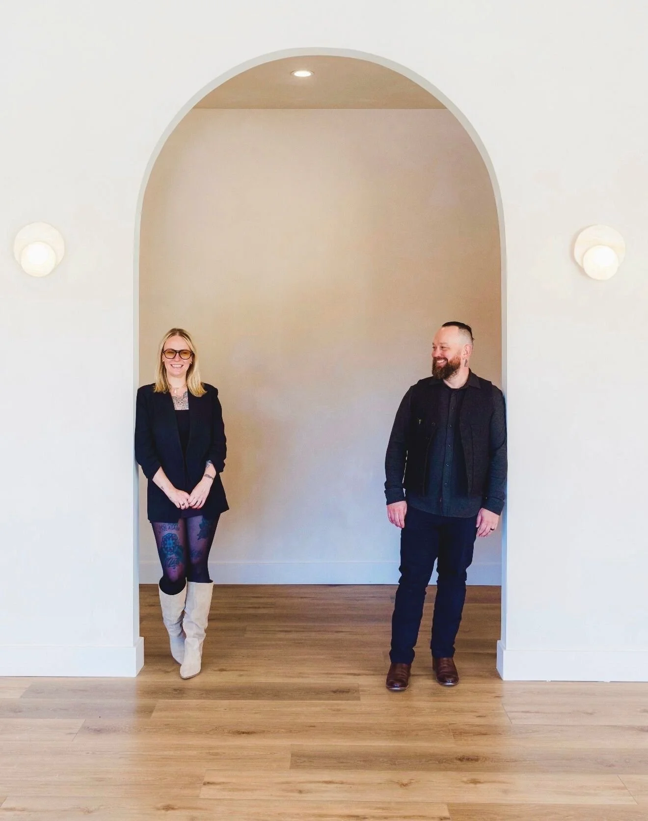 Jessica Ra and Lyle stand together in the space they built, underneath a giant Santa Fe style archway