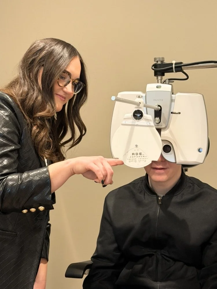 Eye doctor or optometrist conducting an eye exam with a specialized machine on a patient, in a clinical setting.