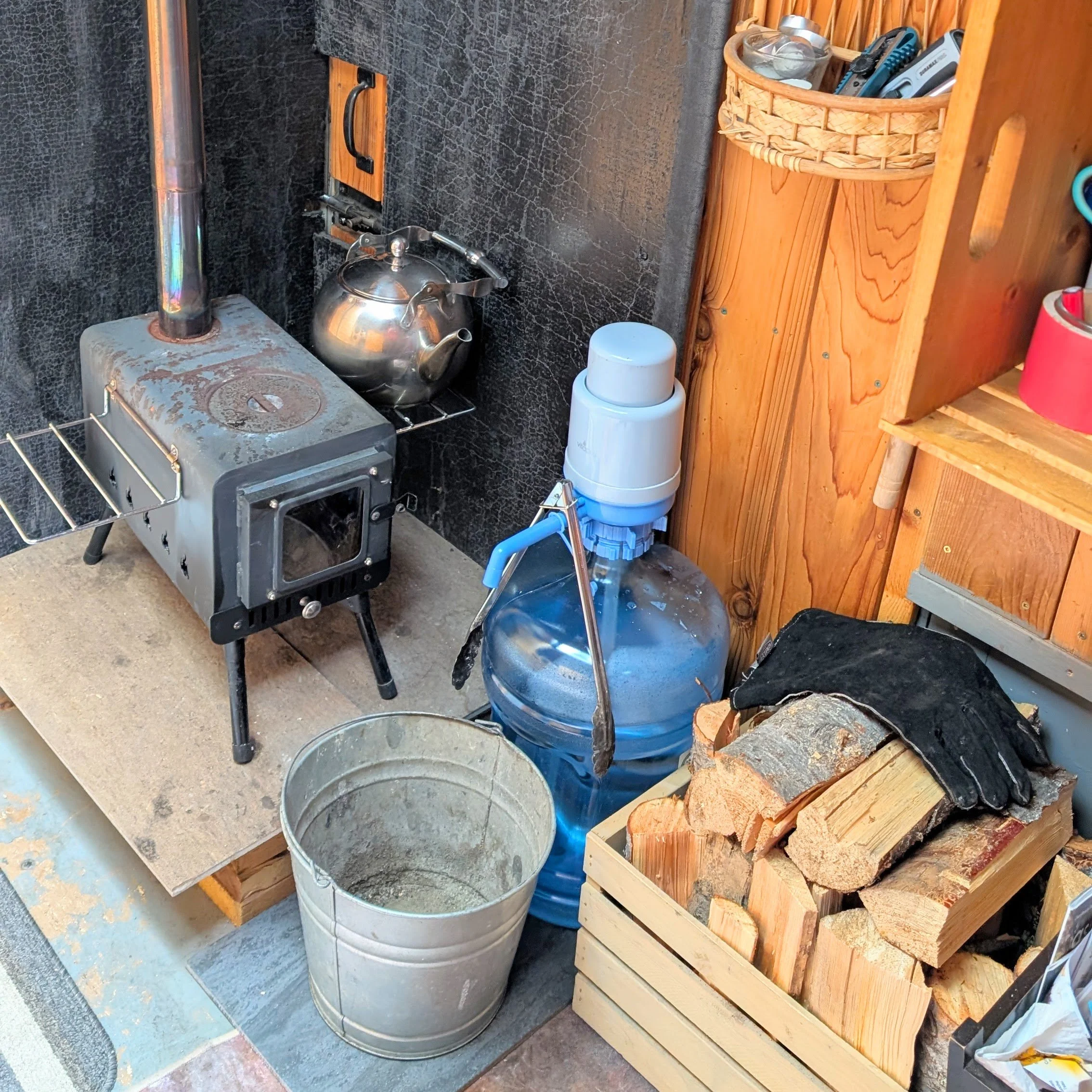 A view of the wood stove, wood box, and potable water jug supplied in the Magic Bus.