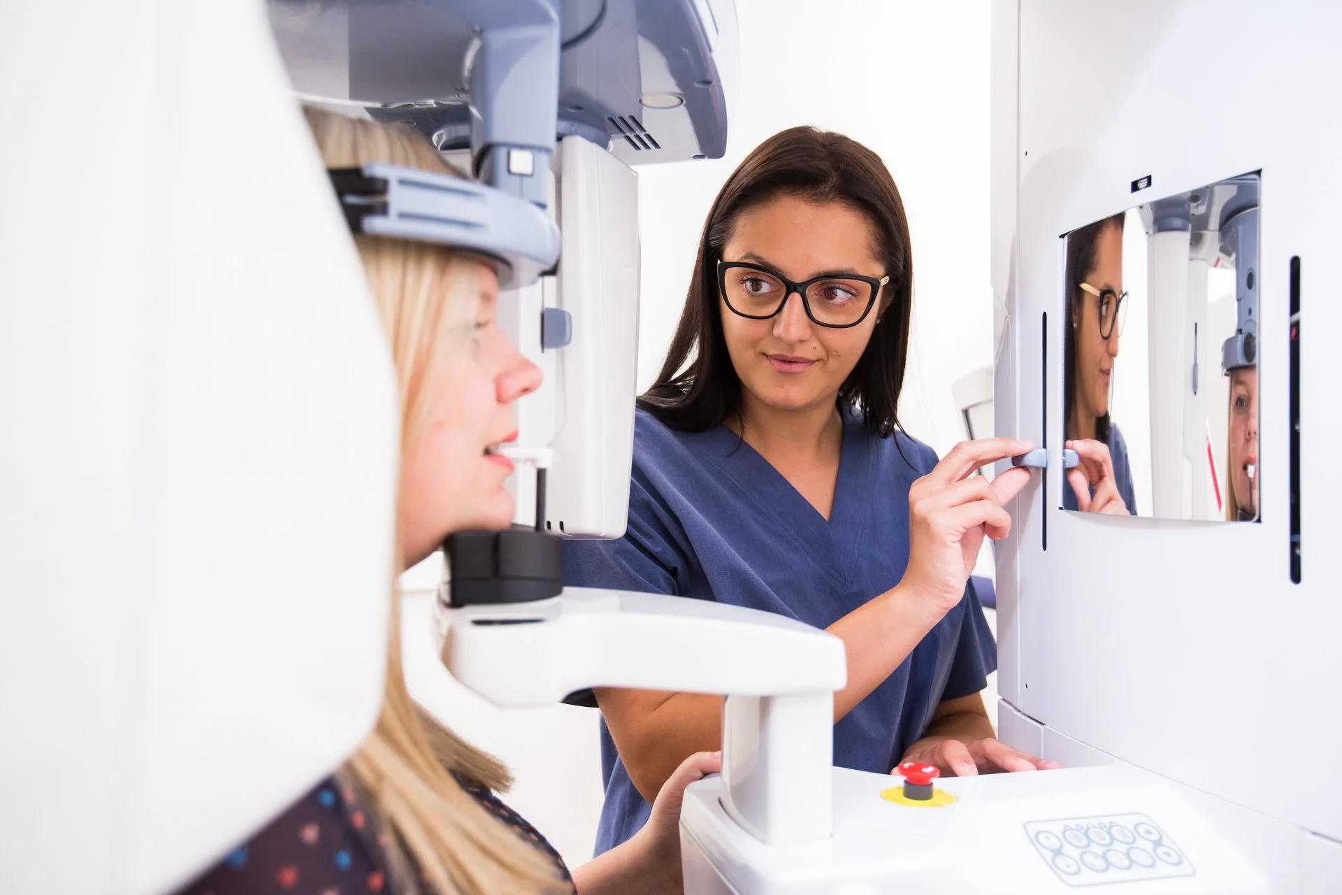 Ärztin führt eine Augentest durch, während eine Patientin vor einem Spiegel sitzt.
