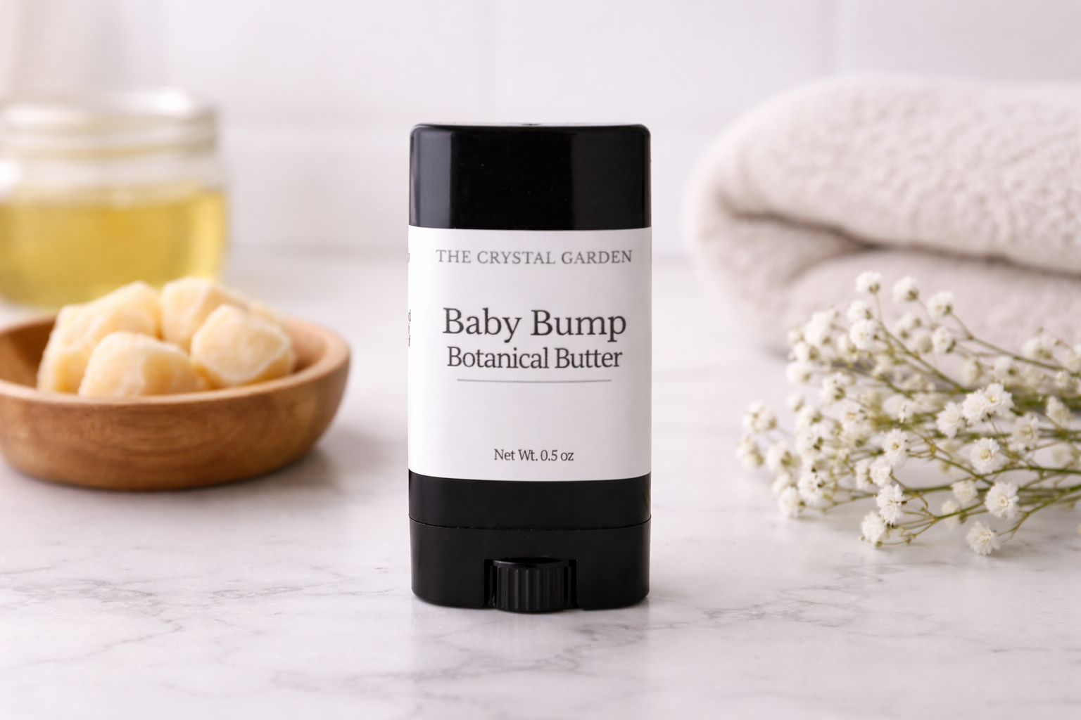 Baby Bump Botanical Butter pregnancy belly butter on a marble countertop with folded towel and botanical butters for daily pregnancy skincare.