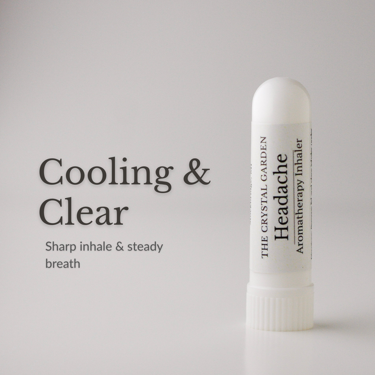 Headache aromatherapy inhaler standing on a neutral surface with a folded towel, glass of water, and candle in a calm minimal setting.