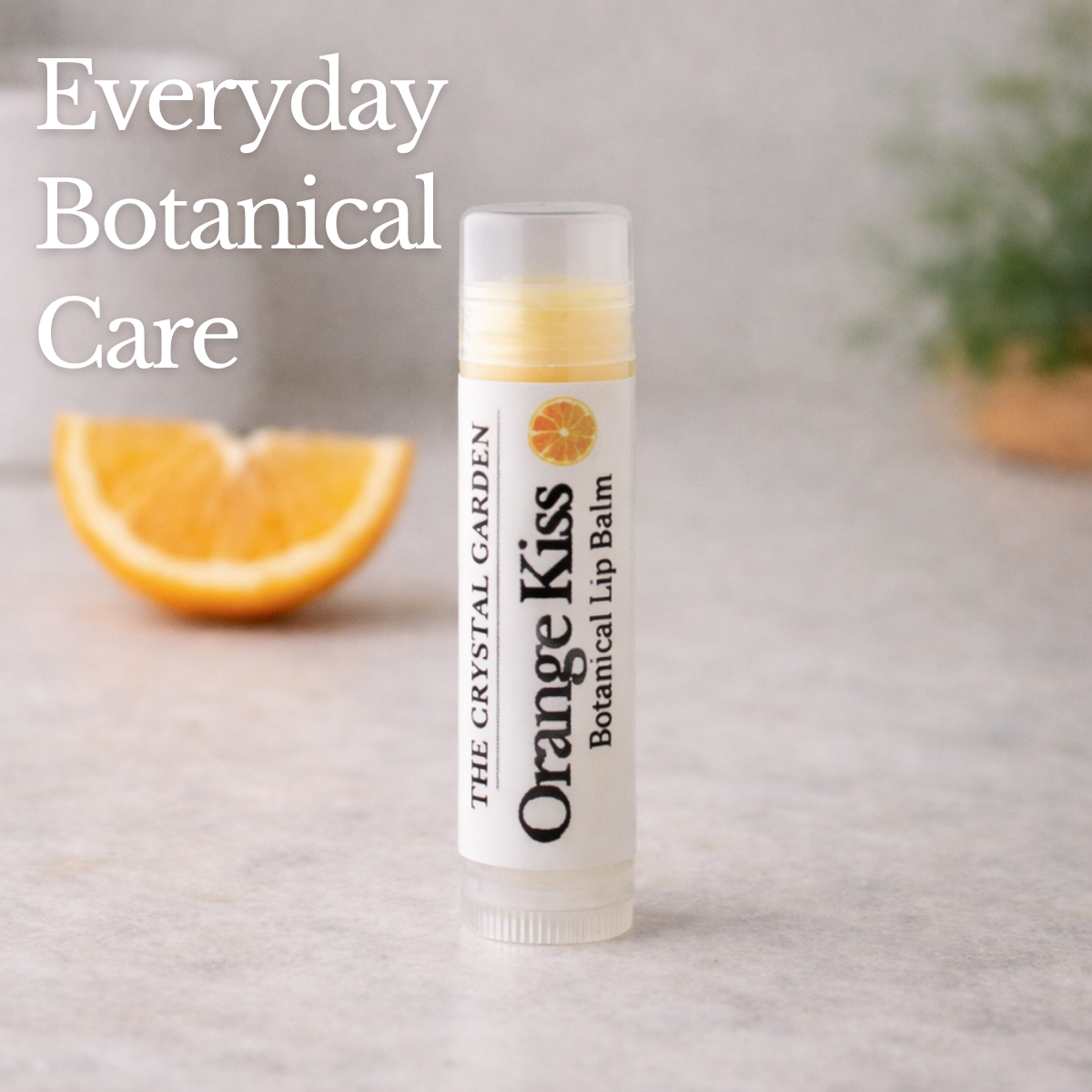 Orange Kiss lip balm styled with dried orange slices and vanilla bean on a soft, light background.