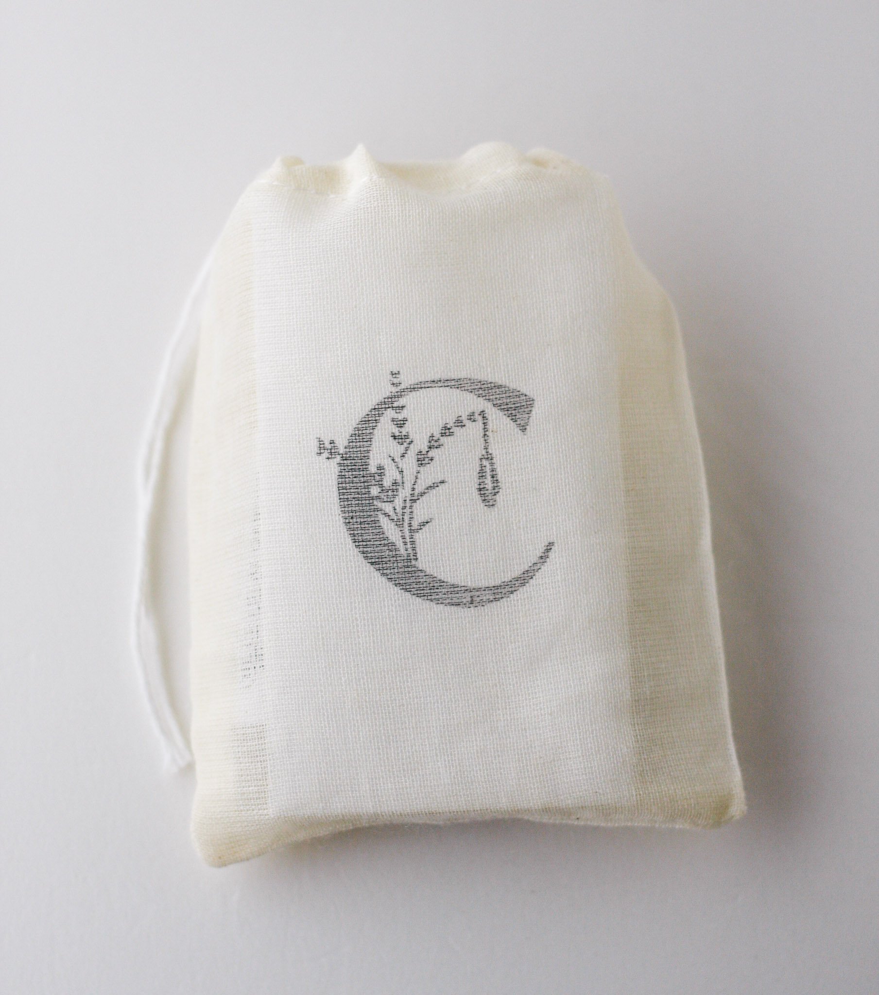 Muslin gift bag with botanical skincare products and The Crystal Garden branding on soft neutral background