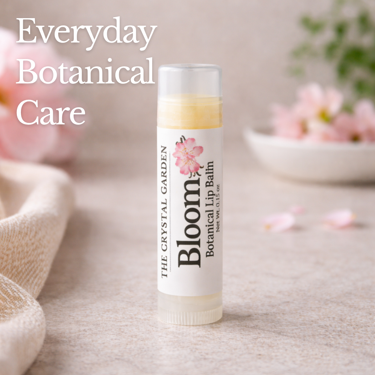 Bloom Botanical lip balm on a stone surface with hibiscus flower and soft neutral background.