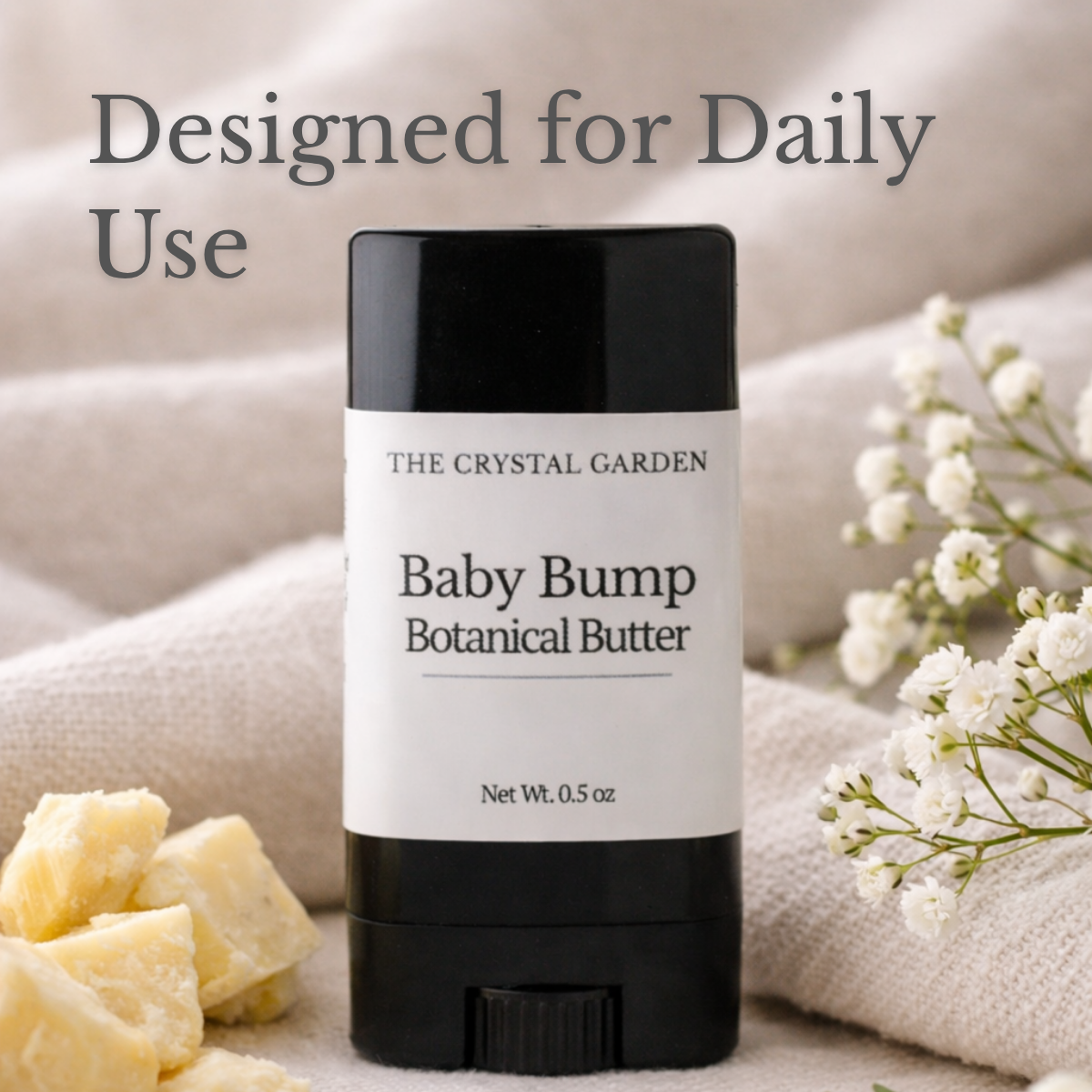 Baby Bump Botanical Butter pregnancy belly butter by The Crystal Garden on soft neutral fabric with botanical butter pieces and delicate white flowers.