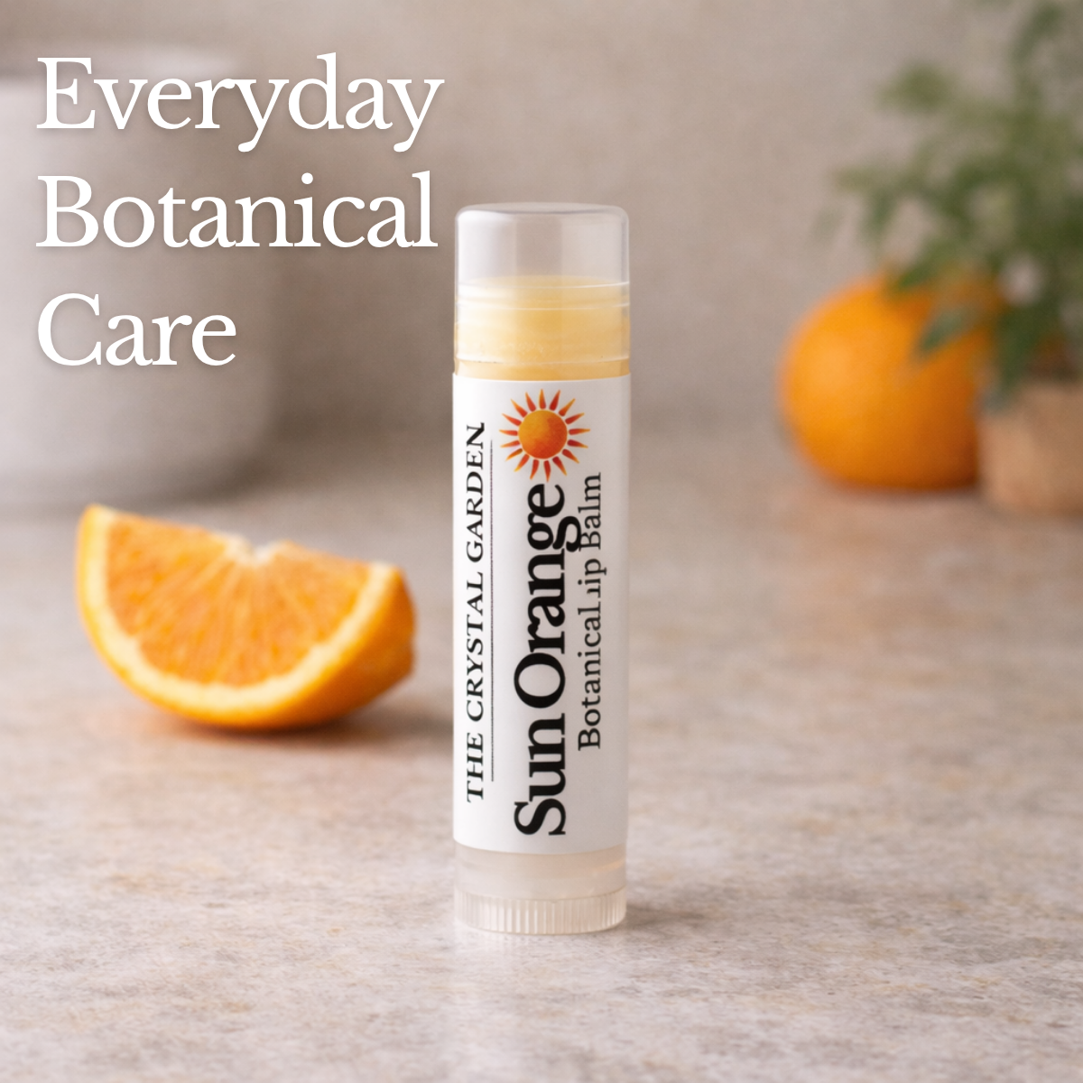 Sun Orange natural lip balm in white tube with botanical label on a white to light gray background, plant-based lip care by The Crystal Garden.