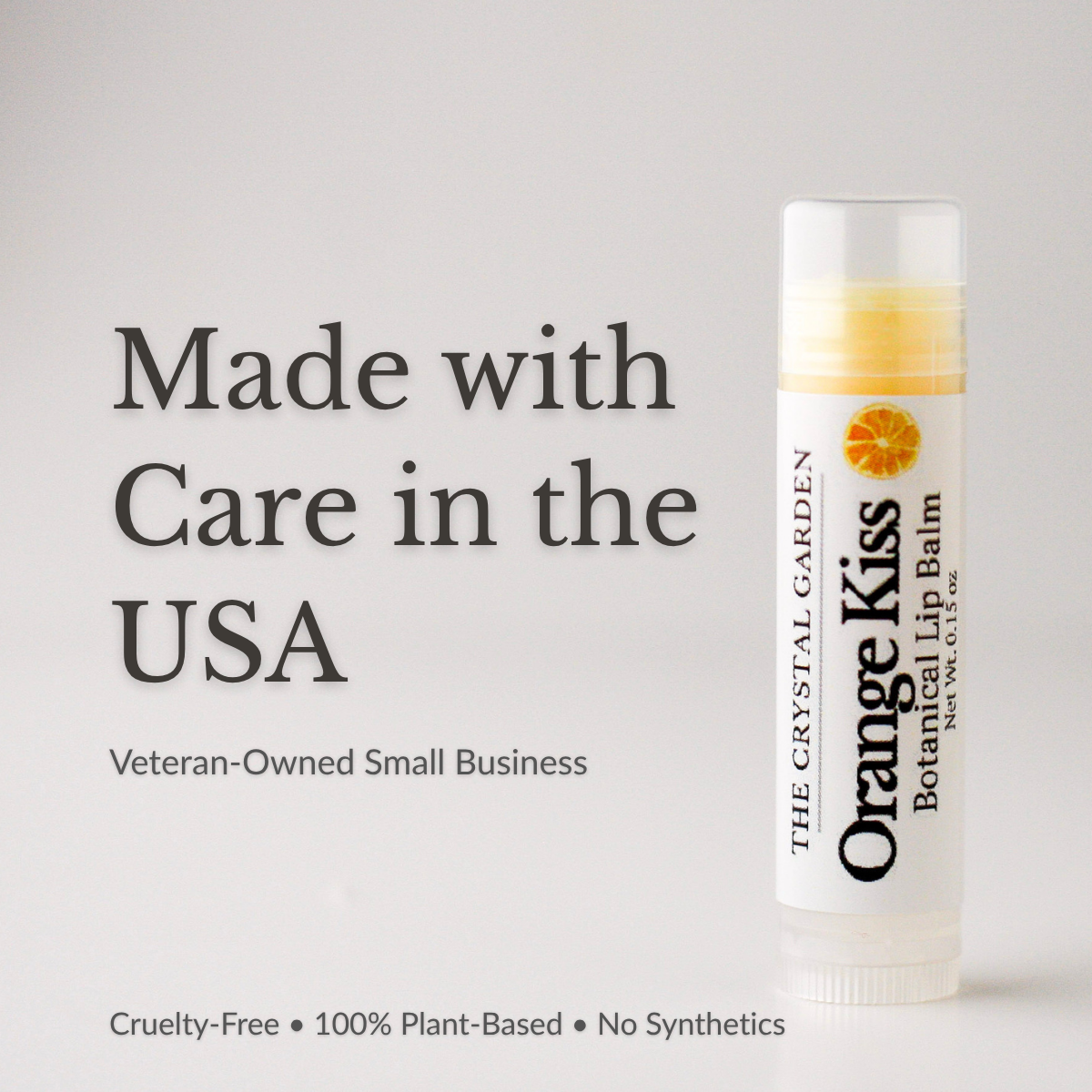 Orange Kiss natural lip balm in white tube with botanical label on a white to light gray background, plant-based lip care by The Crystal Garden.
