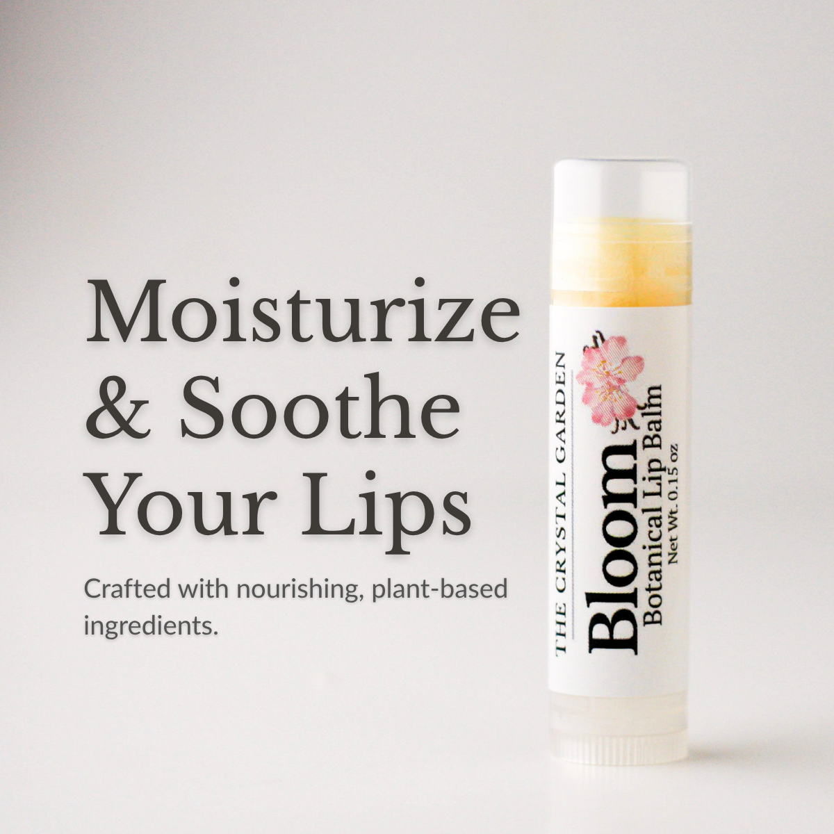 Bloom Botanical natural lip balm in white tube with botanical label on a white to light gray background, plant-based lip care by The Crystal Garden.
