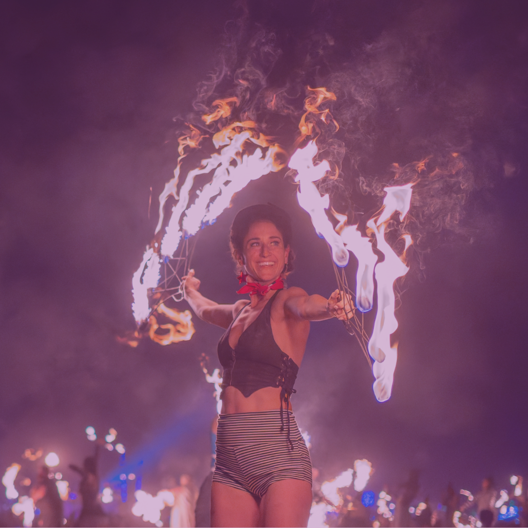 A person with short hair is in a dark room illuminated by pink and purple lights, standing against a patterned wall.