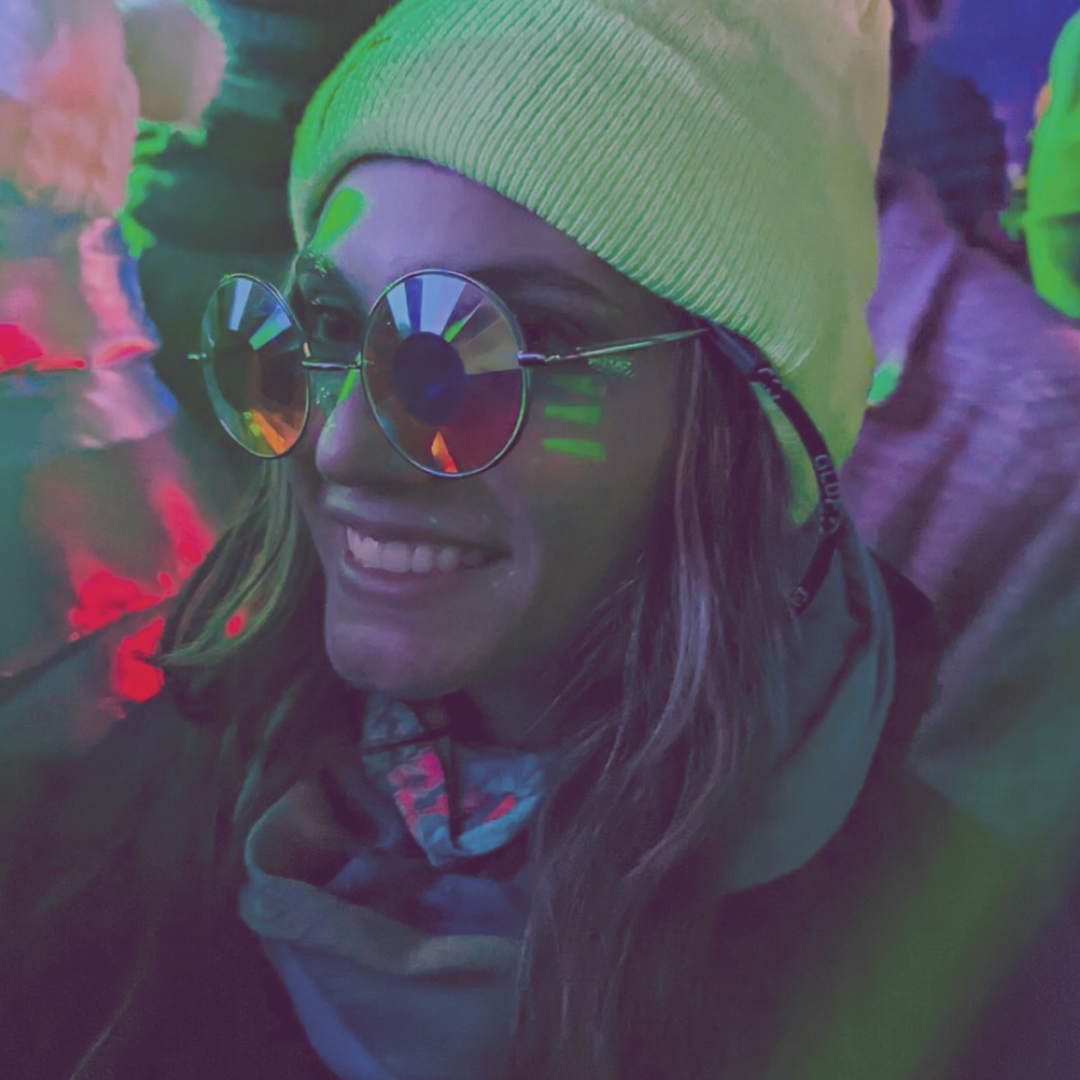 A girl smiling with glasses on at a rave
