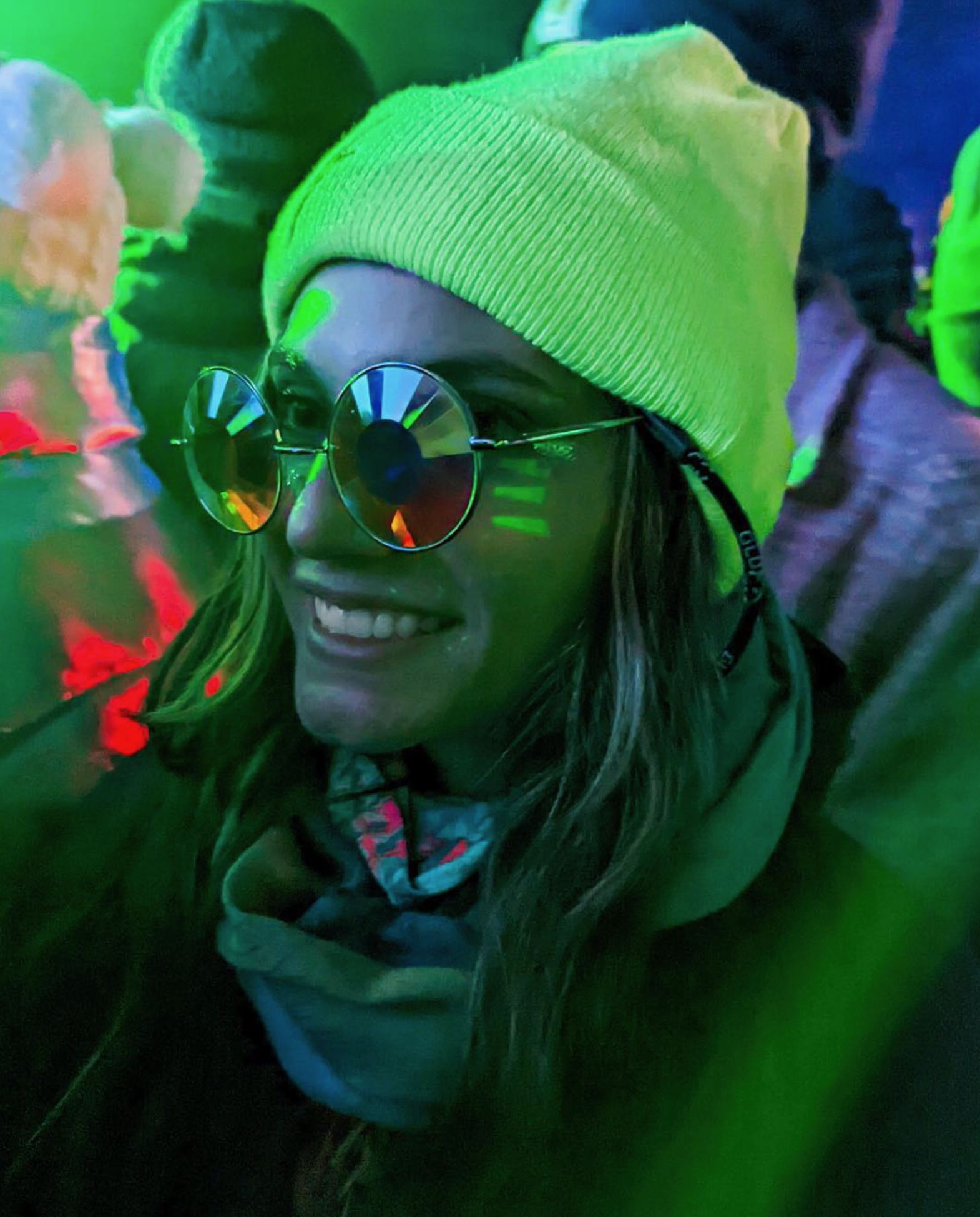 A girl smiling with glasses on at a rave