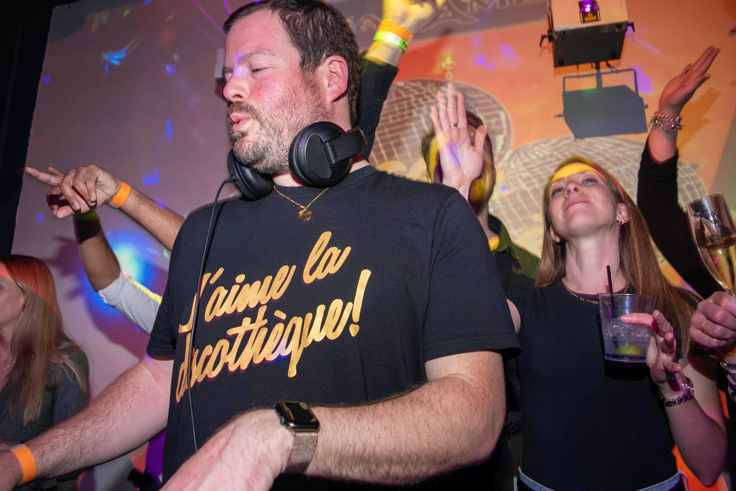 A DJ's hand adjusting controls on a green-lit DJ mixer or turntable.