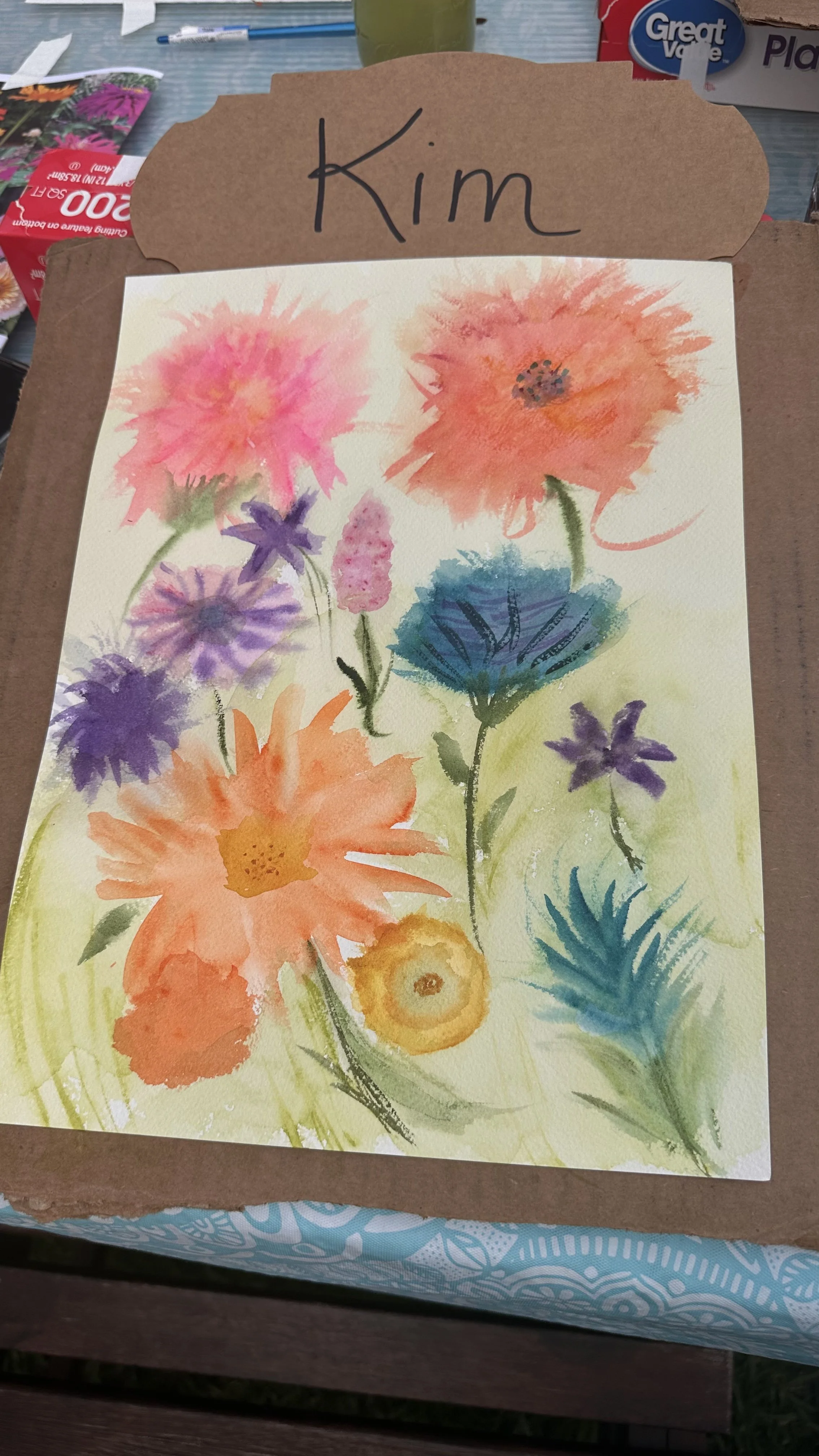 A watercolor painting of colorful flowers, with the name "Kim" written on a brown cardboard backing.