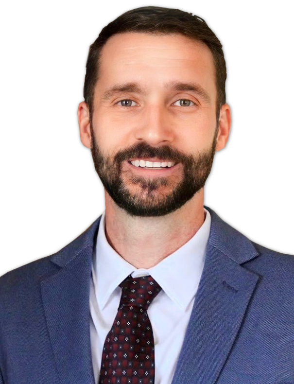 Portrait of a man with dark hair and beard, wearing a blue suit, white shirt, and patterned tie, against a black background.