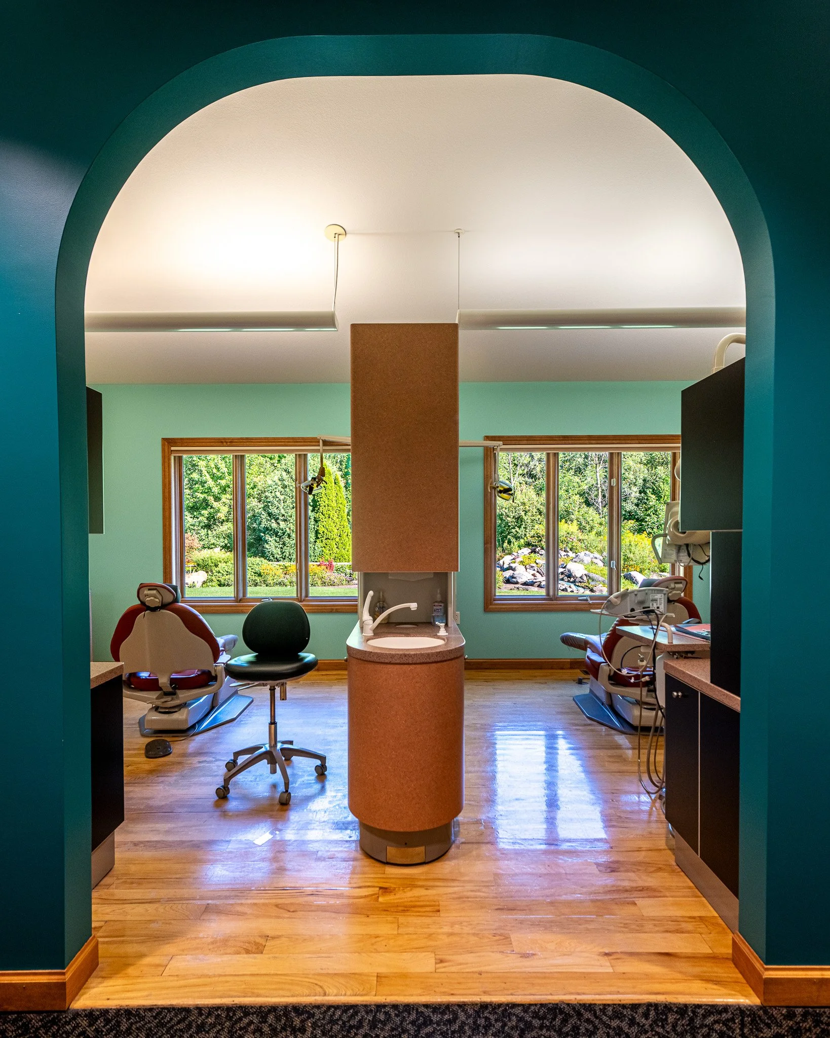 New Chapter Dentistry's treatment rooms with dental chairs, windows overlooking greenery, and dental equipment.