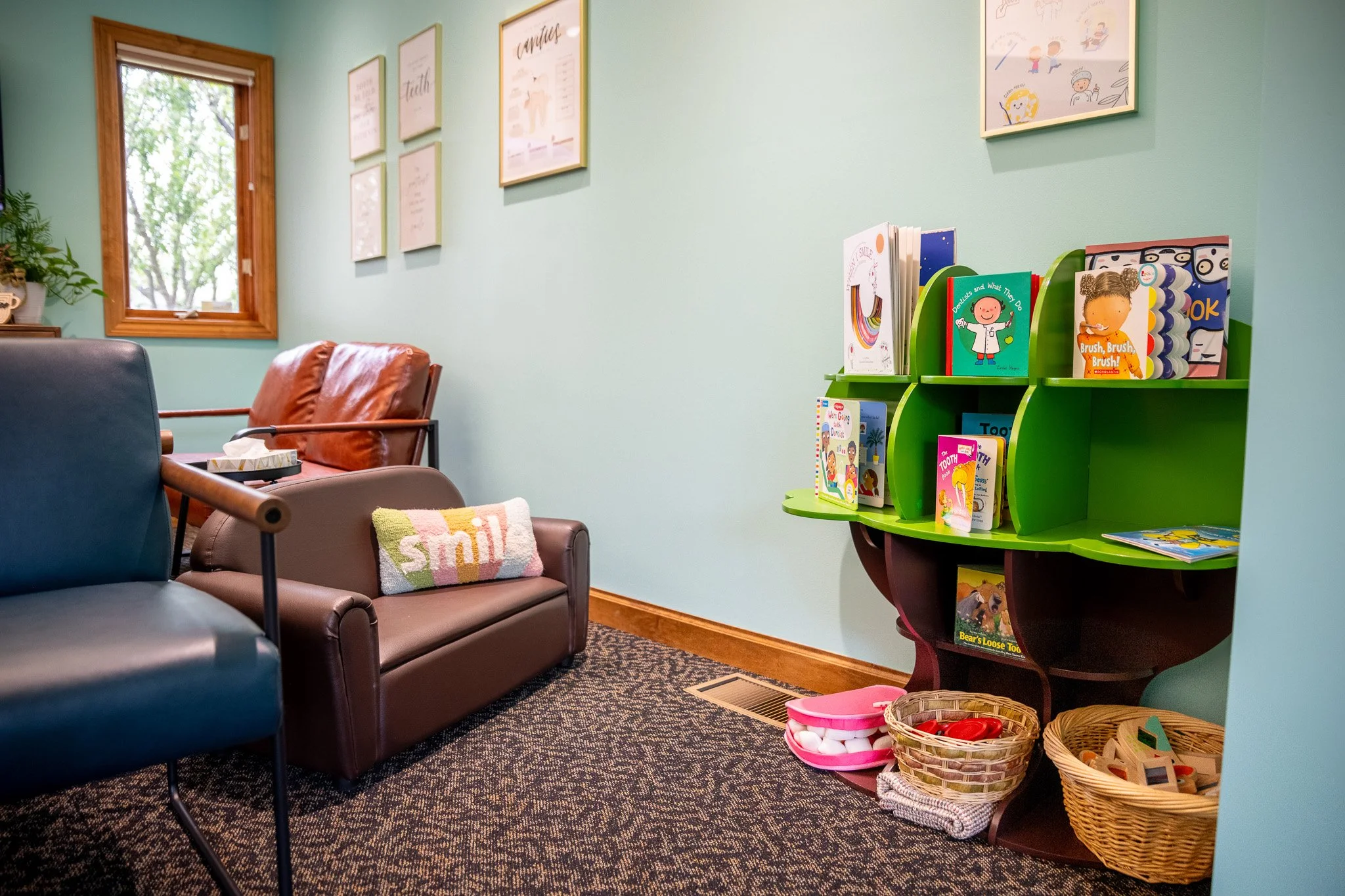New Chapter Dentistry's waiting room with colorful bookshelf, children's books, and woven baskets containing toys and supplies.