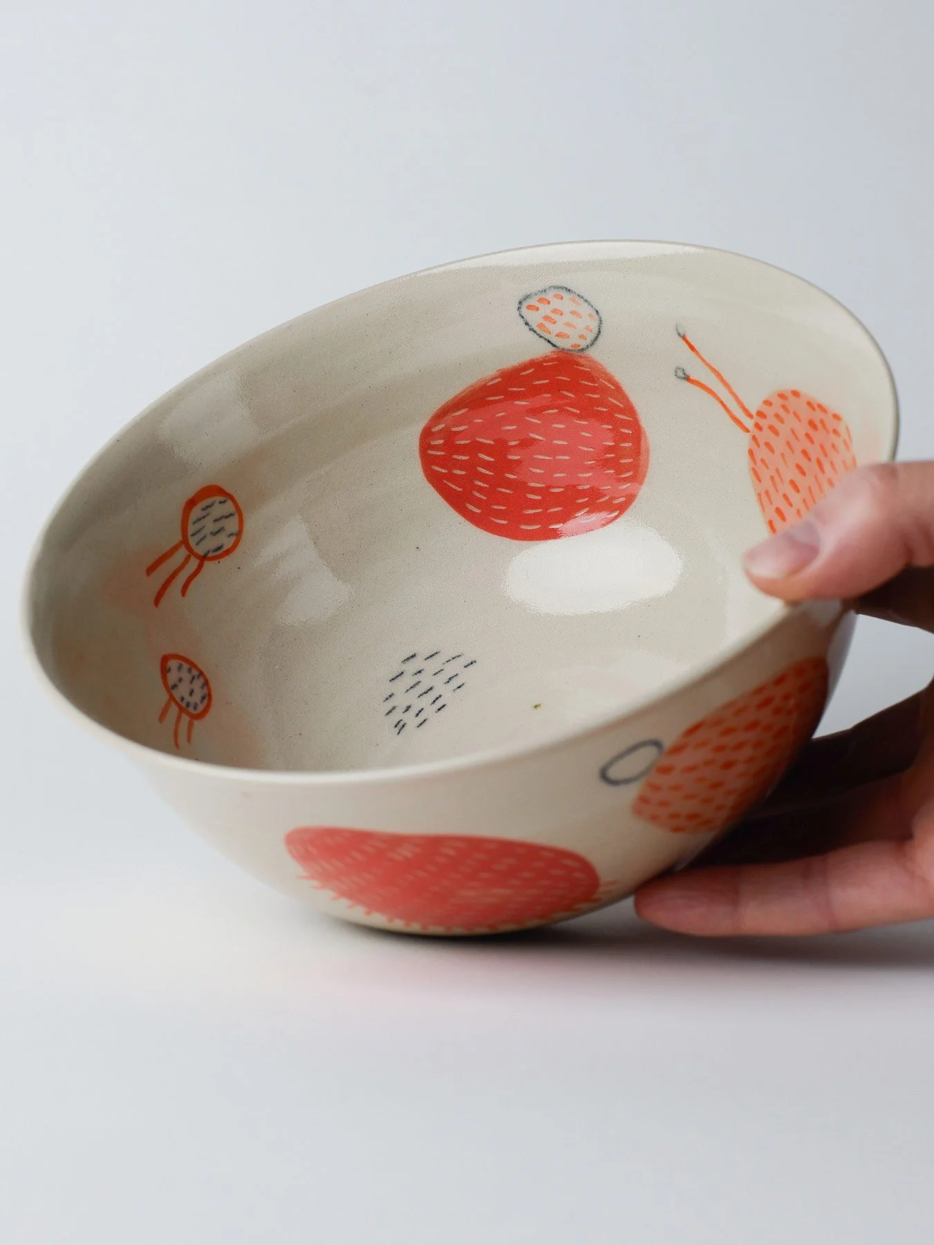 Udon-Schale mit gezeichneten roten Wesen – in der Hand gehaltene Schale, Einblick in die Innenglasur.